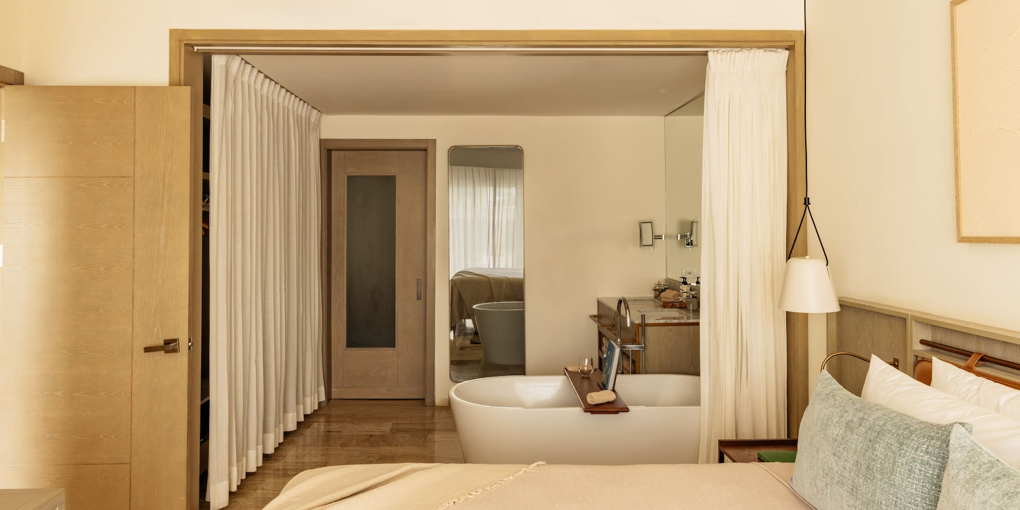 Luxury open-plan bedroom and bathroom with freestanding tub, modern design.