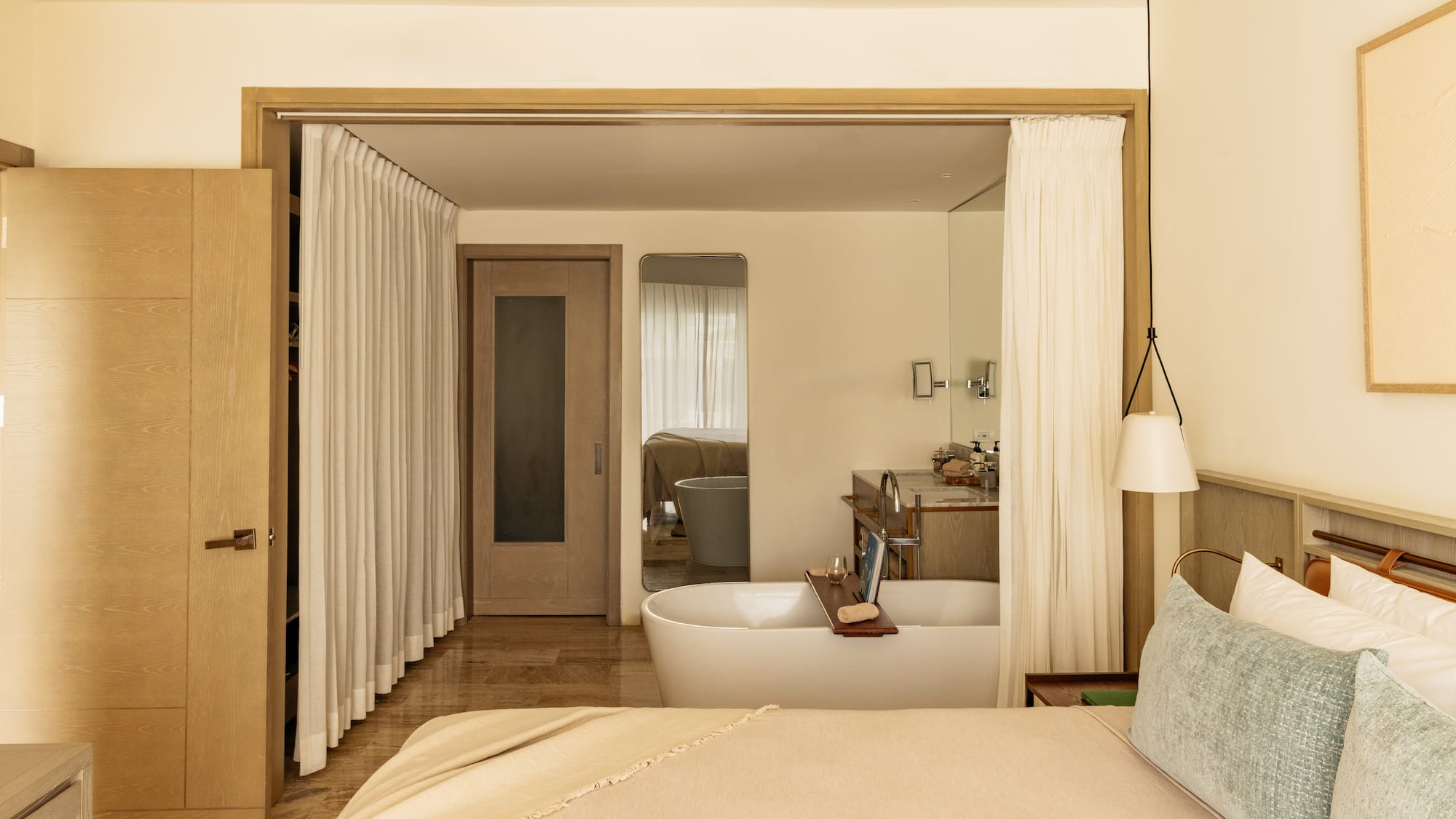 Luxury open-plan bedroom and bathroom with freestanding tub, modern design.