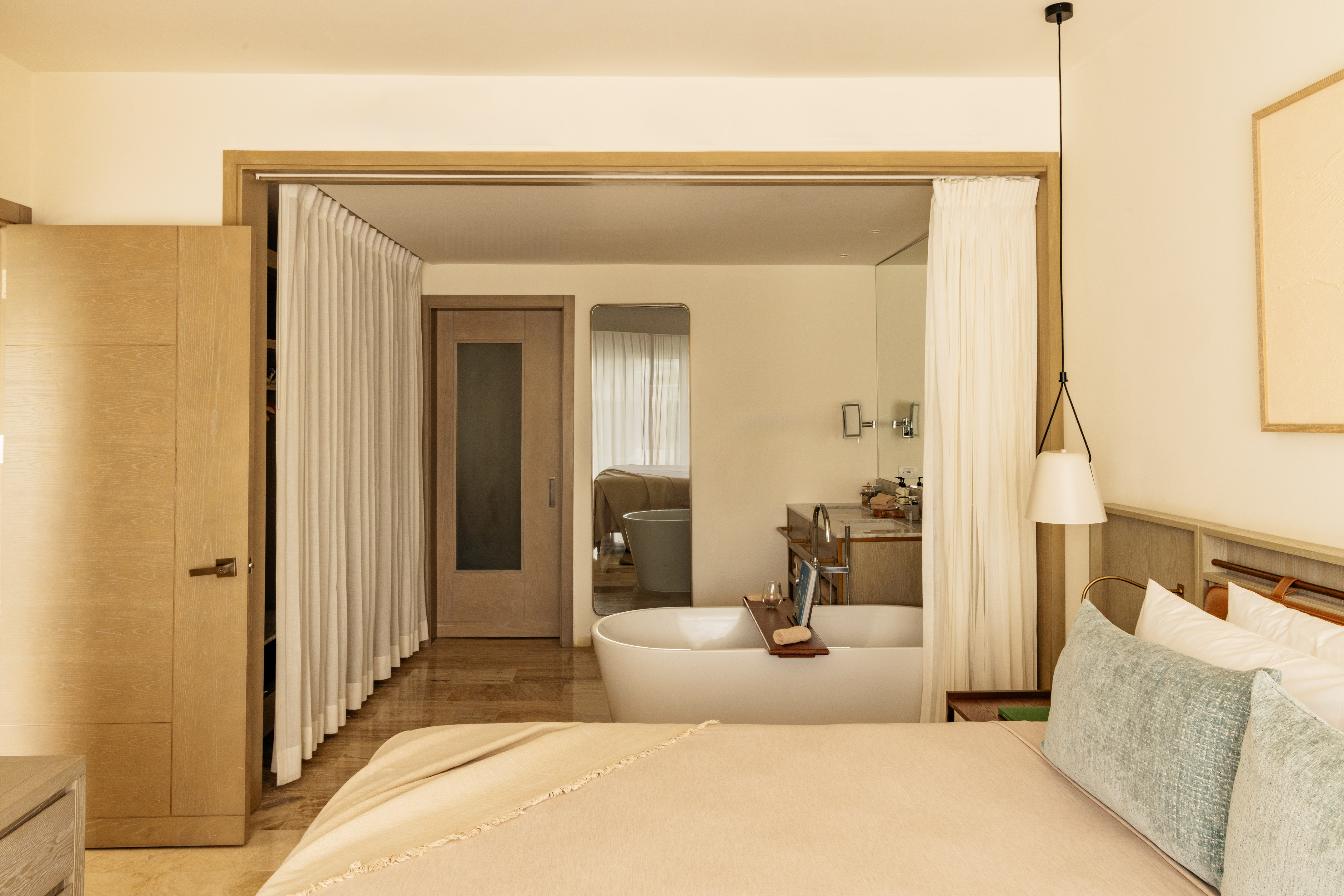 Luxury open-plan bedroom and bathroom with freestanding tub, modern design.