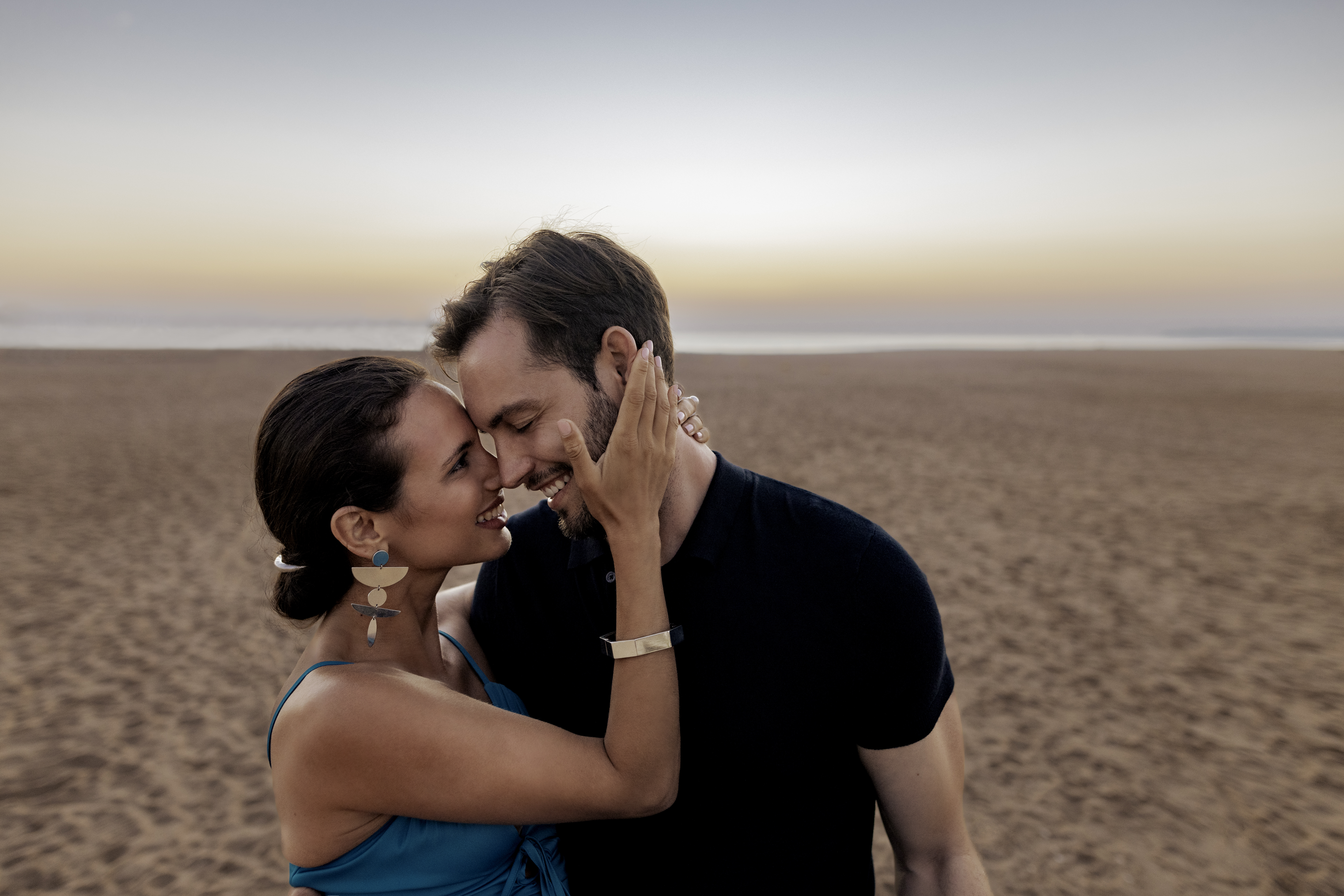 a man and woman hugging on a beach