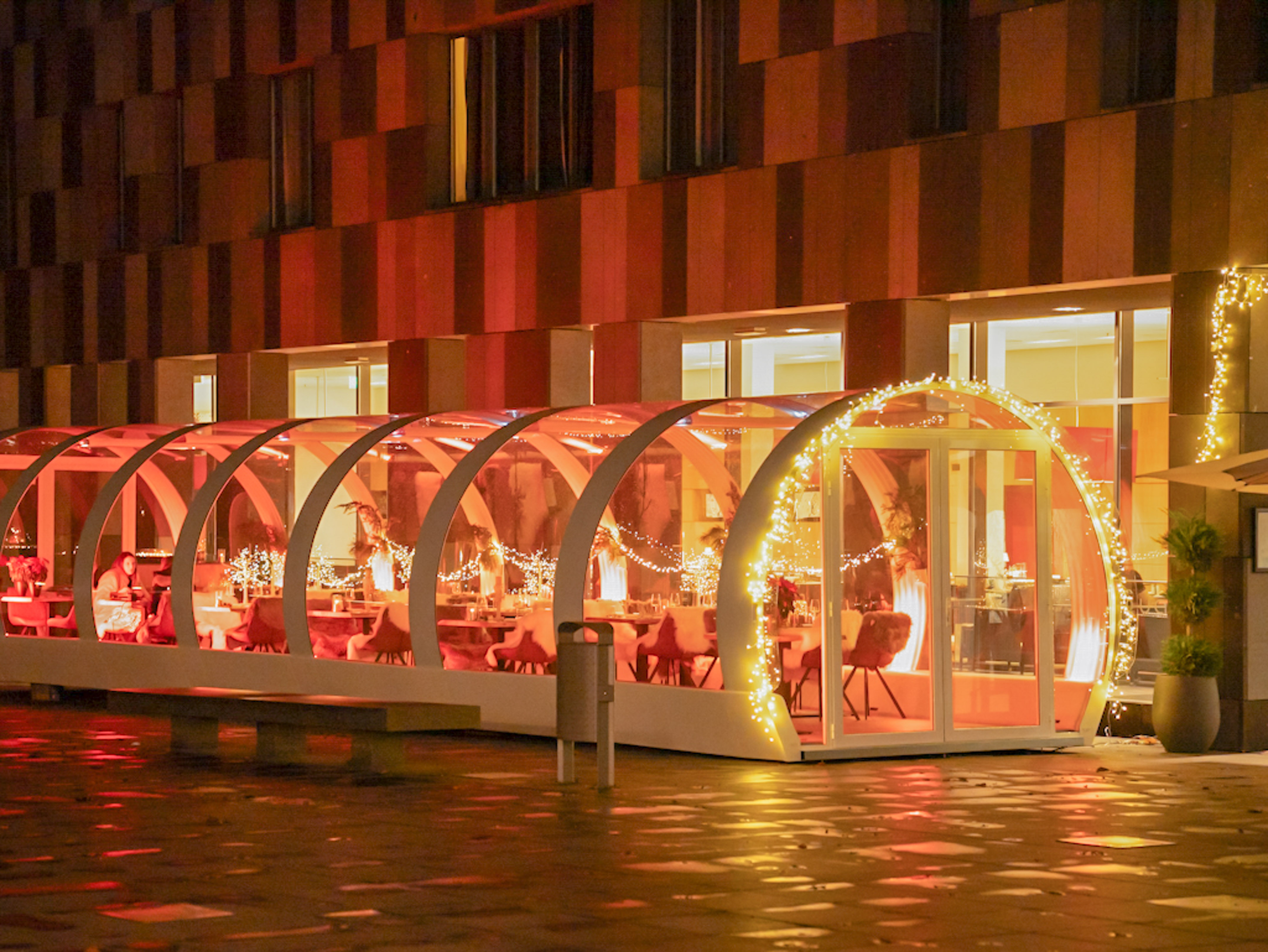 a glass structure with lights outside of a building