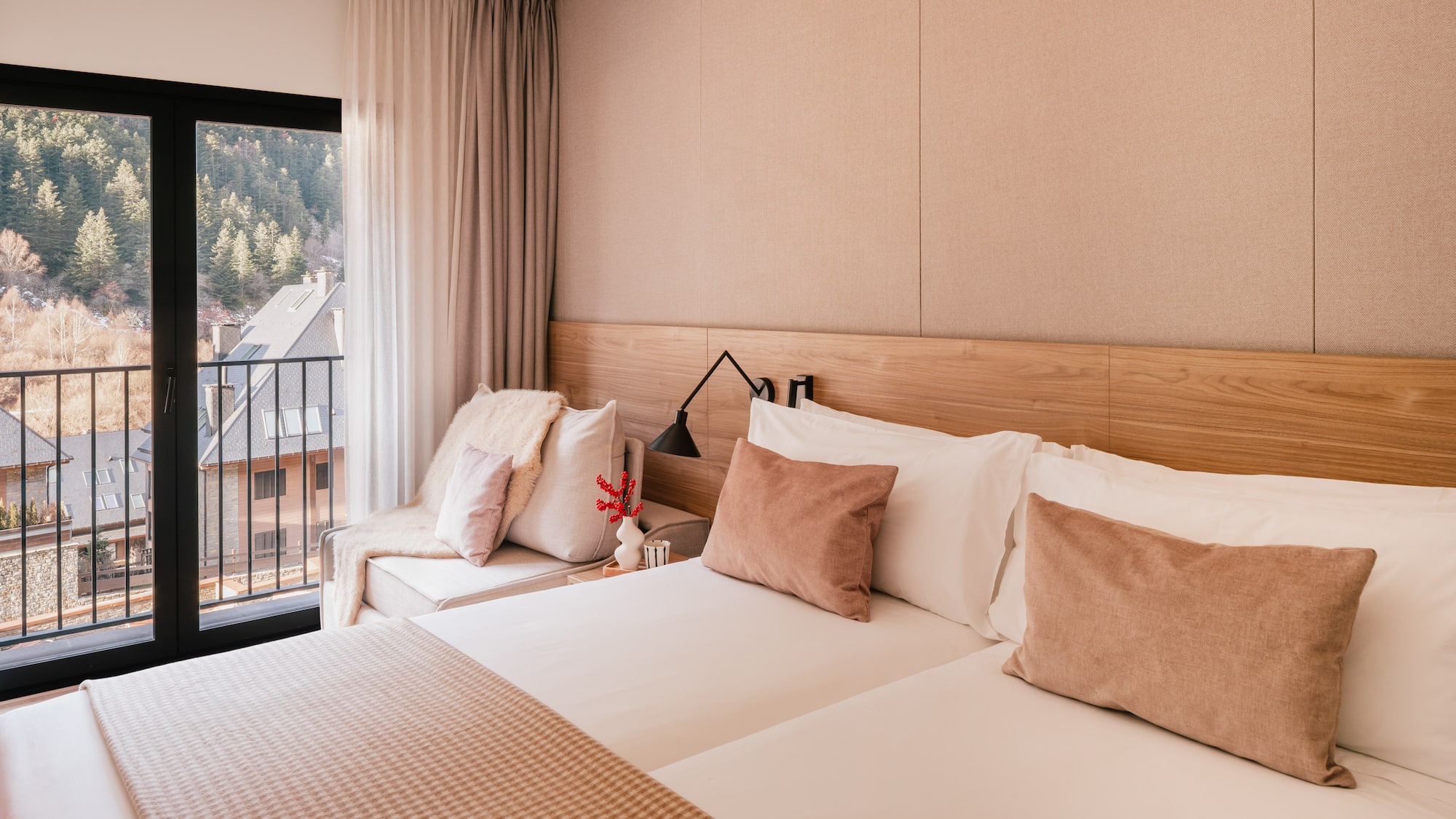 Modern hotel room with mountain view balcony and neutral wooden decor.