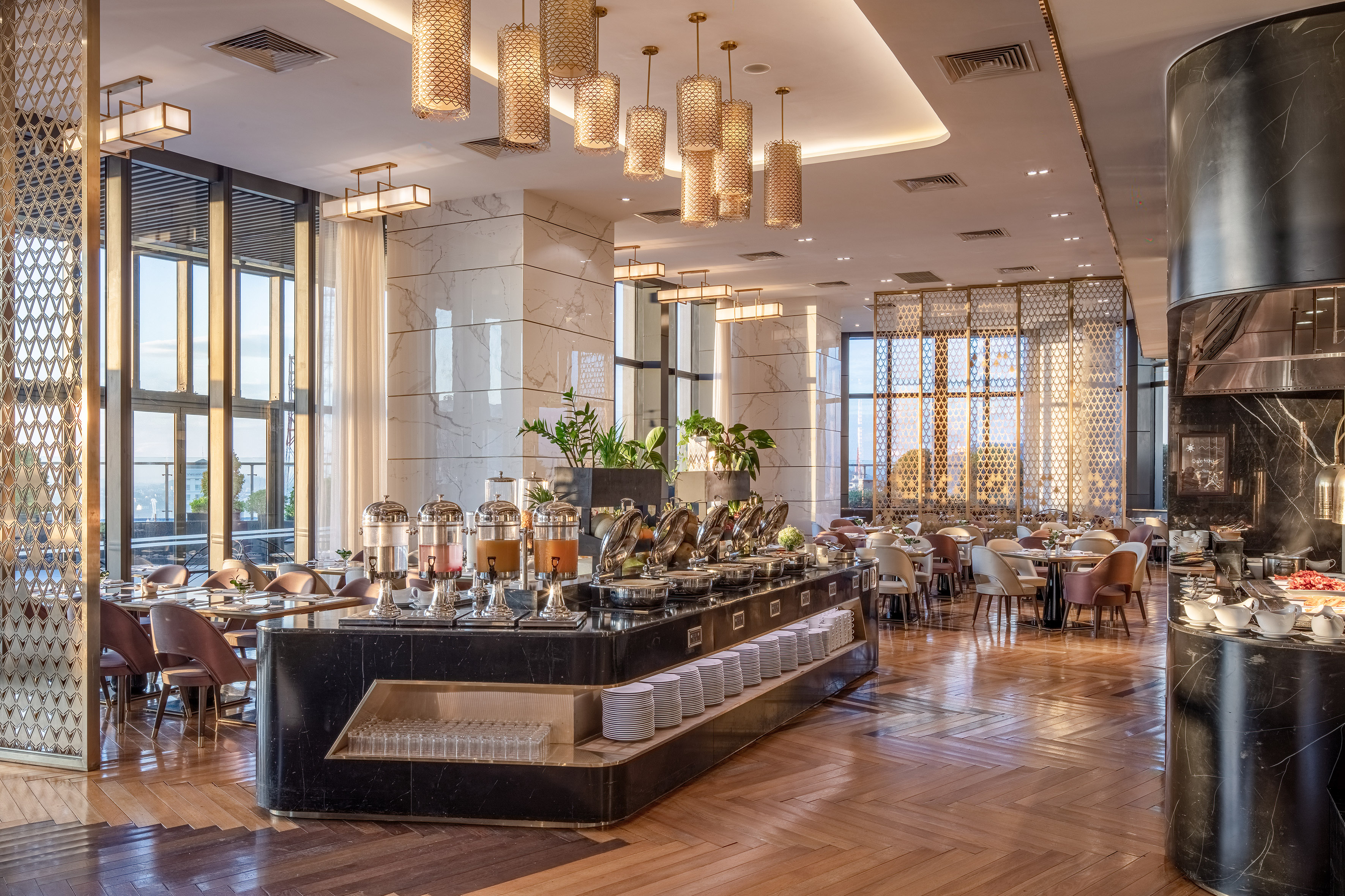Modern hotel buffet restaurant interior with marble, golden lights, and food displays.