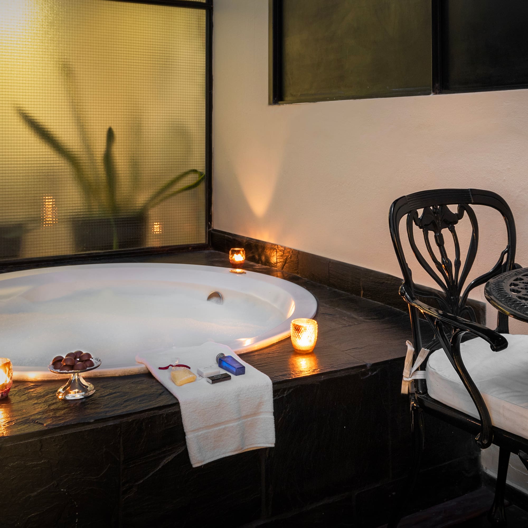 a hot tub with candles and a chair