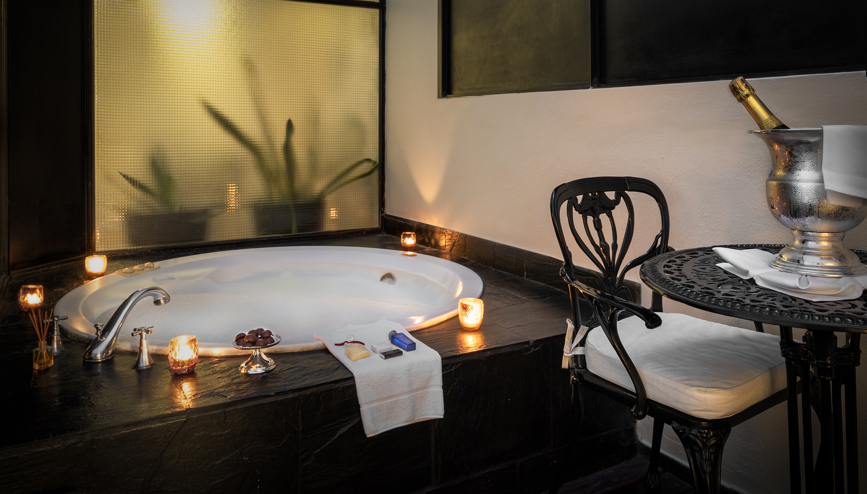 Romantic hot tub suite with candles, champagne, and chocolates.