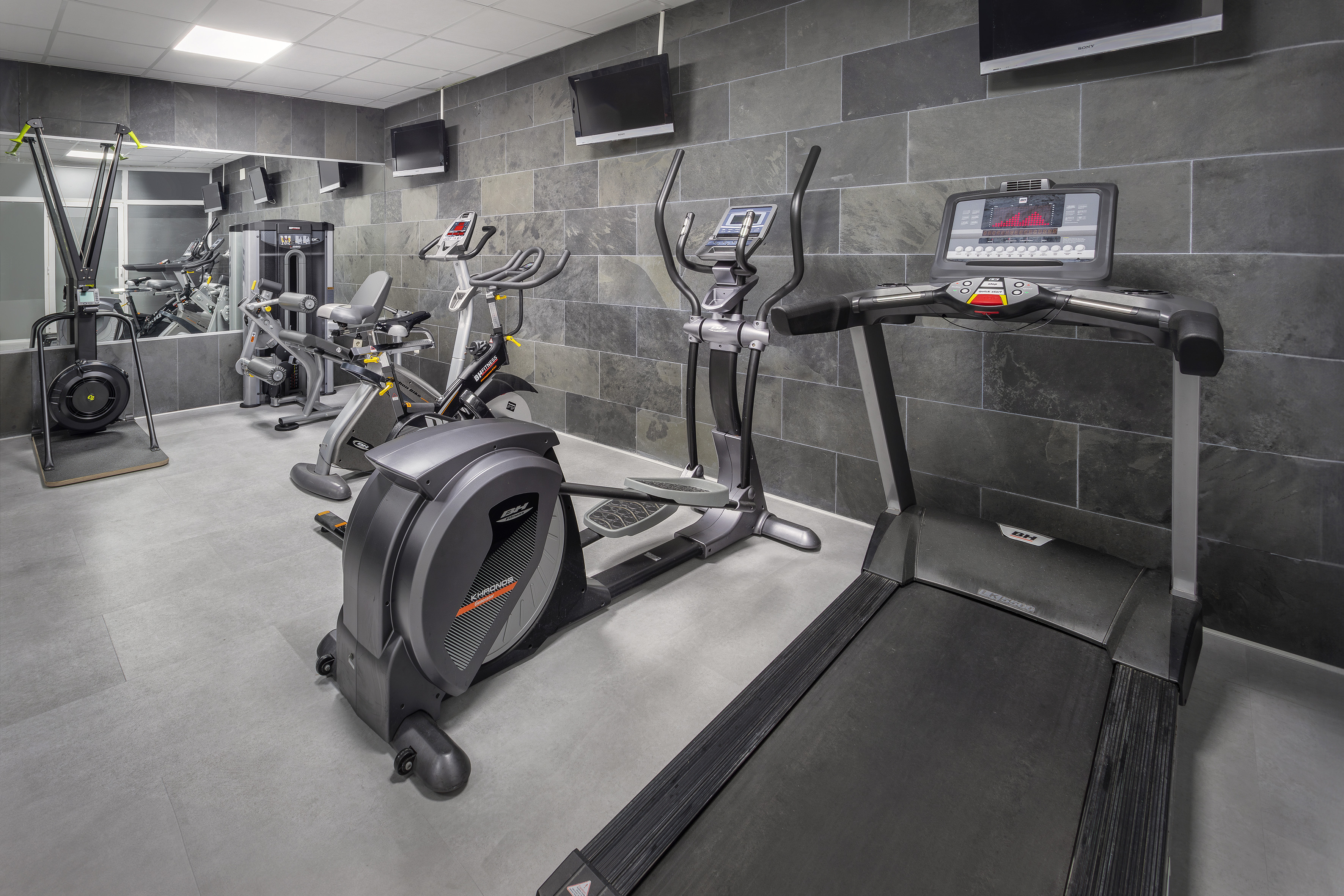 Gimnasio moderno con cinta de correr, elíptica, bicicleta y máquinas.