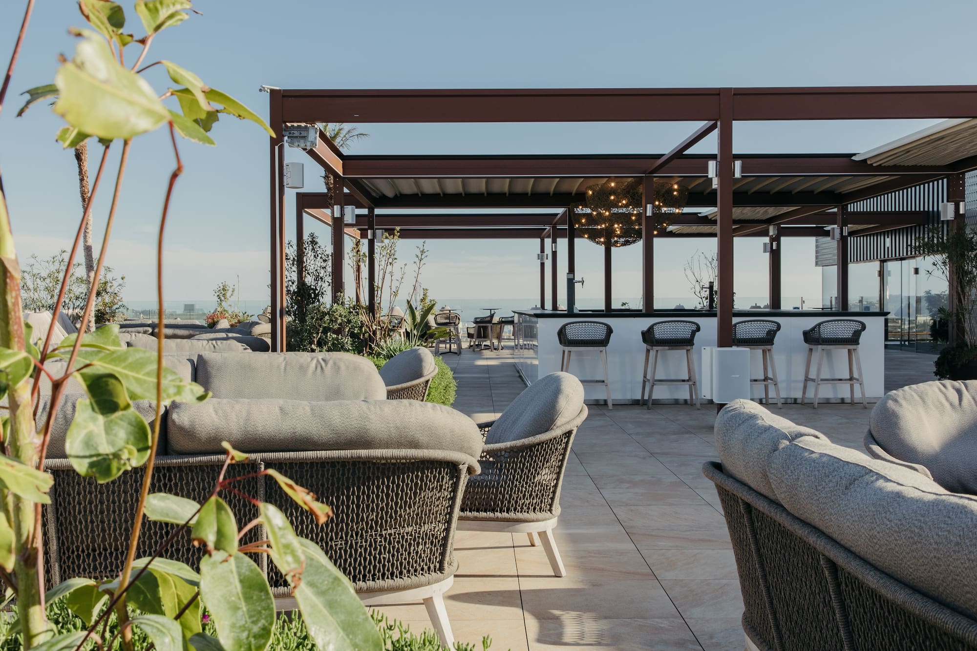 Rooftop bar and lounge with comfortable outdoor seating and ocean view.