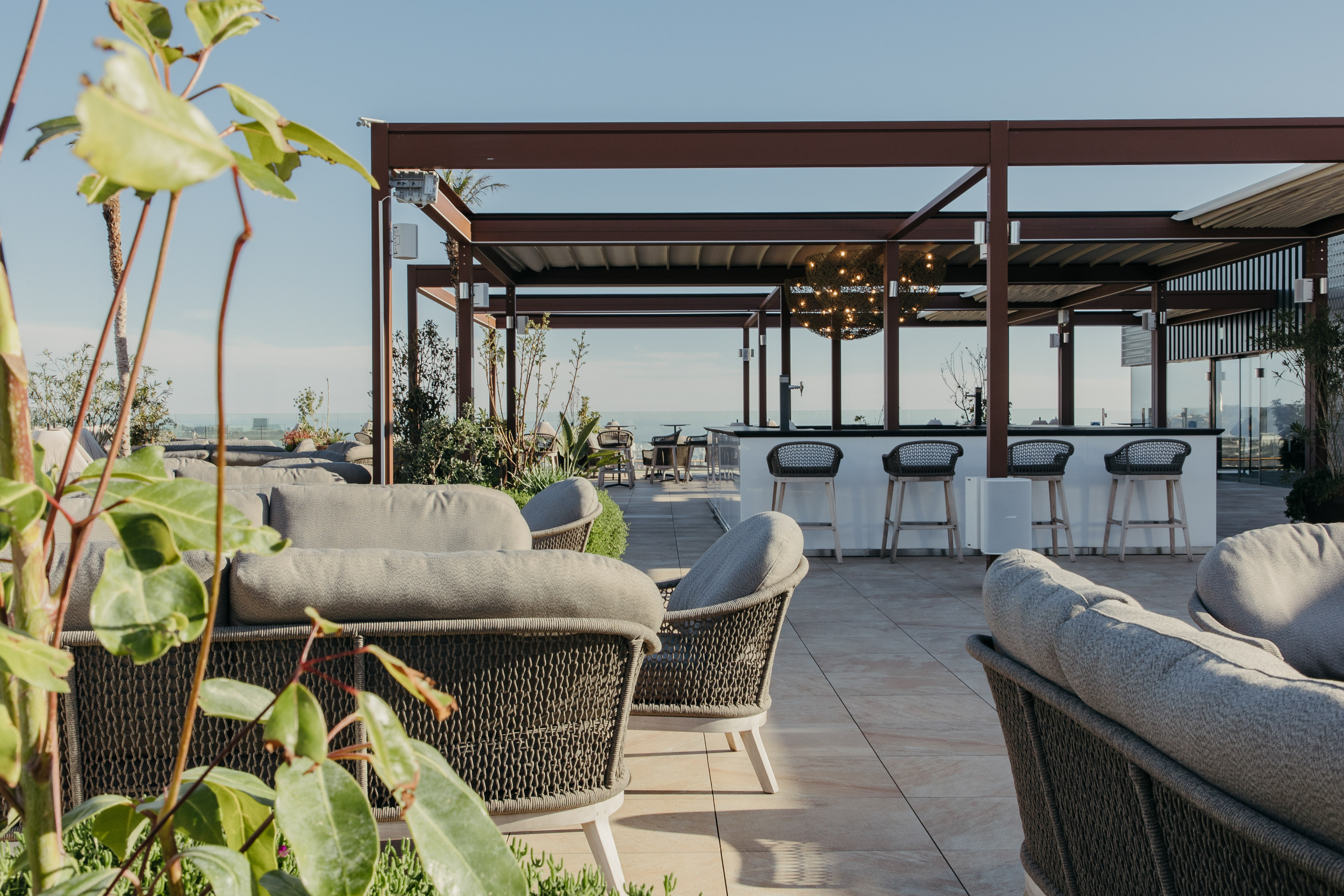Rooftop bar and lounge with comfortable outdoor seating and ocean view.