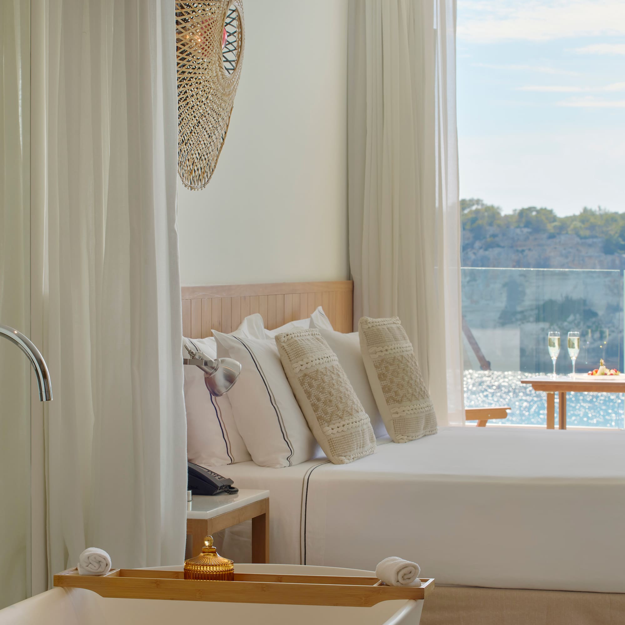 a bed with pillows in a room with a view of water and trees