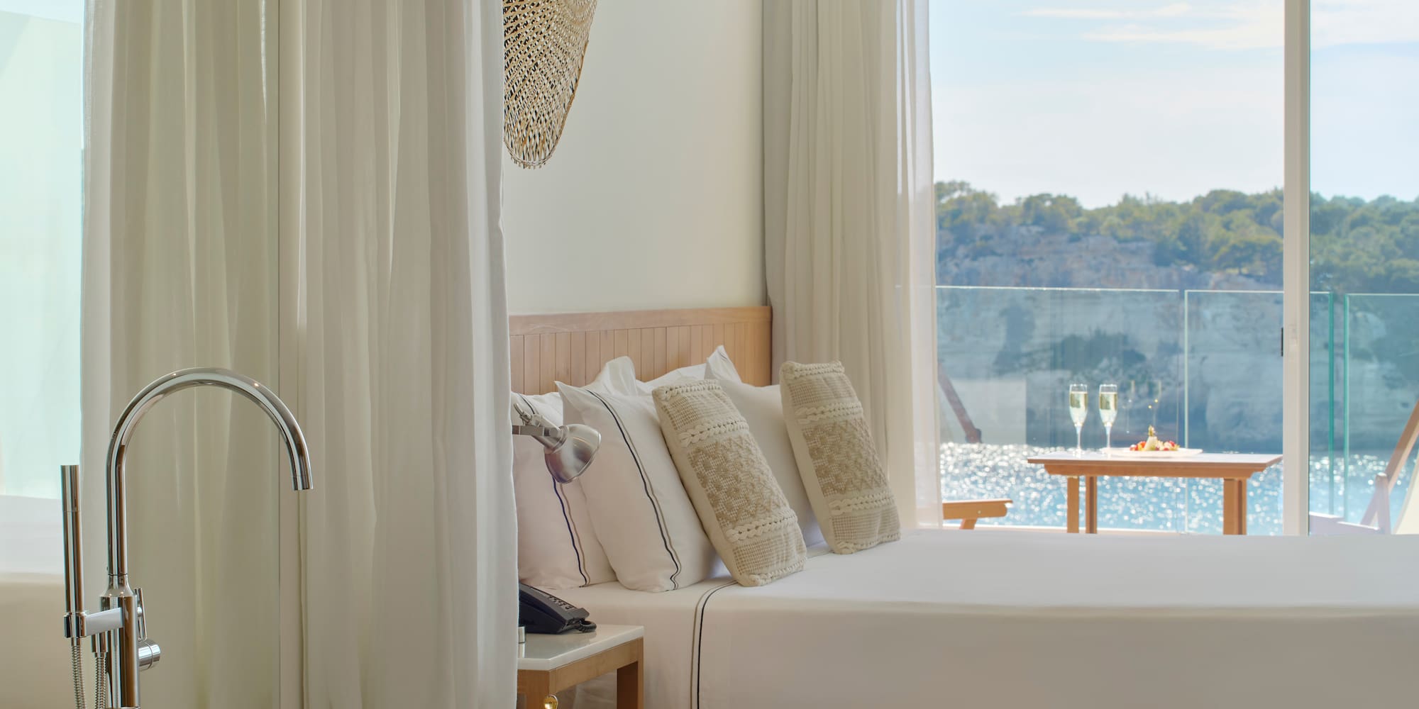 a bed with pillows in a room with a view of water and trees
