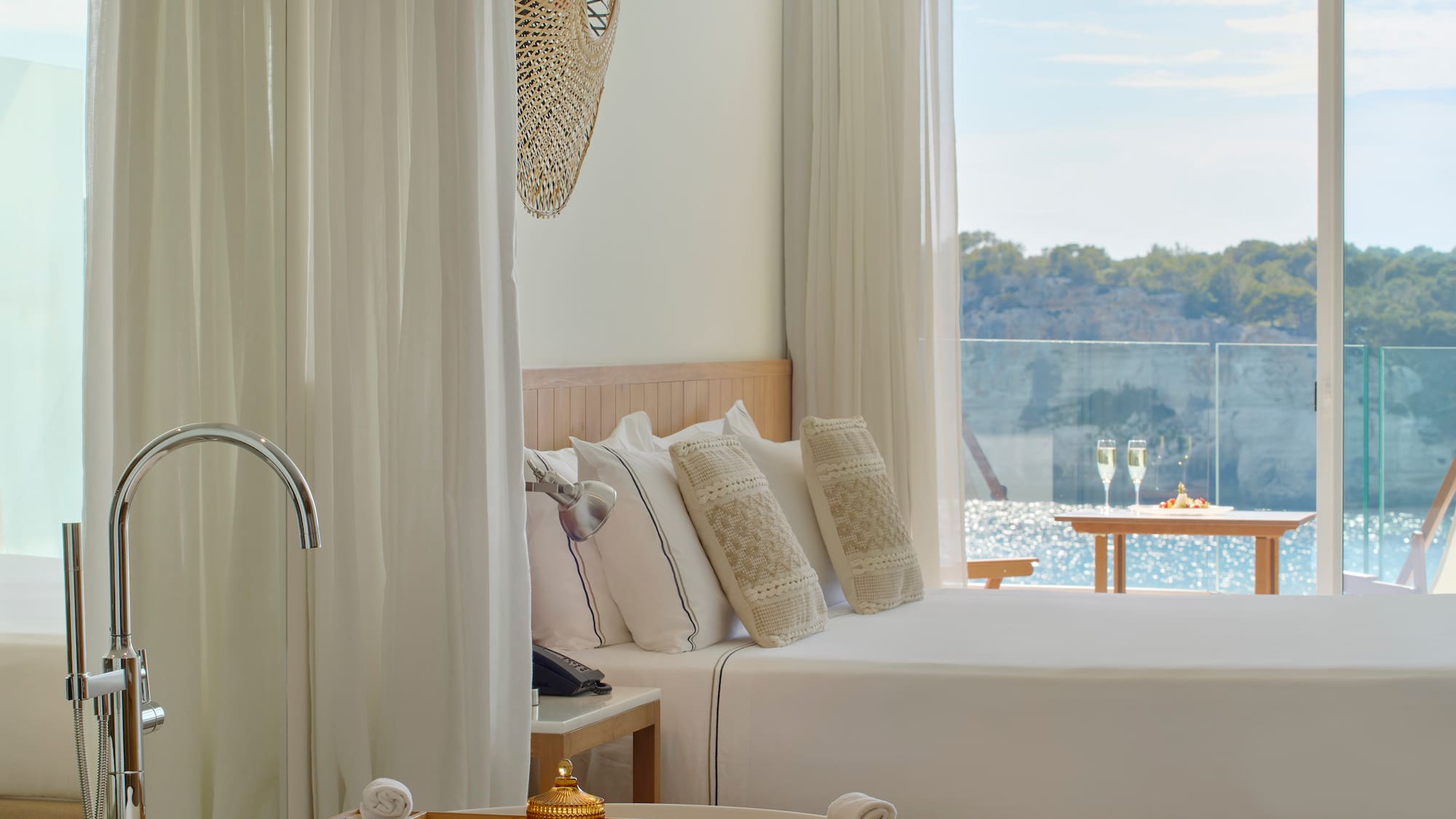 a bed with pillows in a room with a view of water and trees