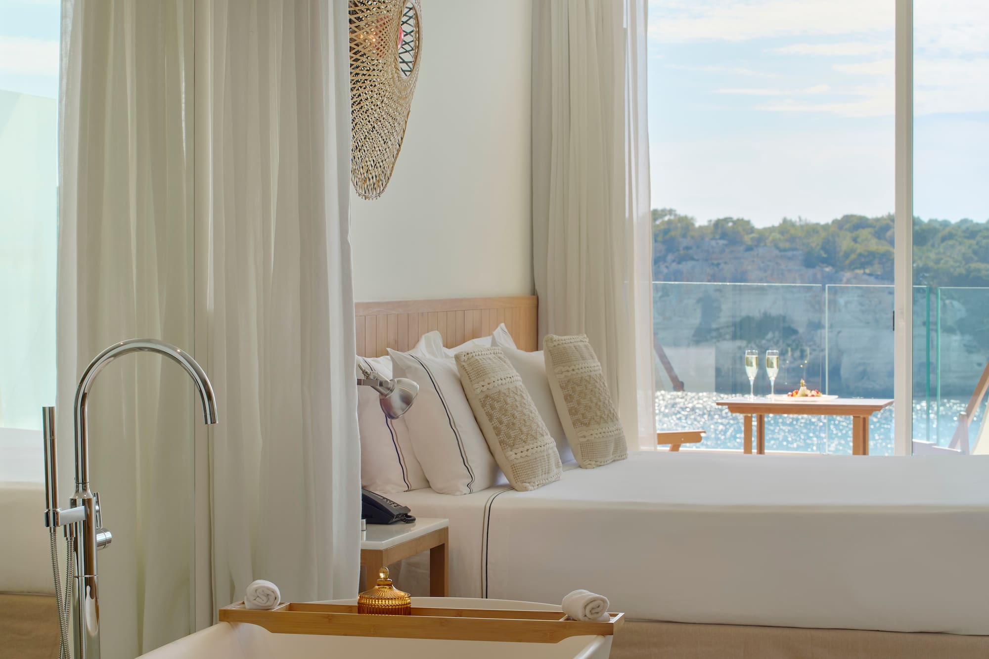 a bed with pillows in a room with a view of water and trees