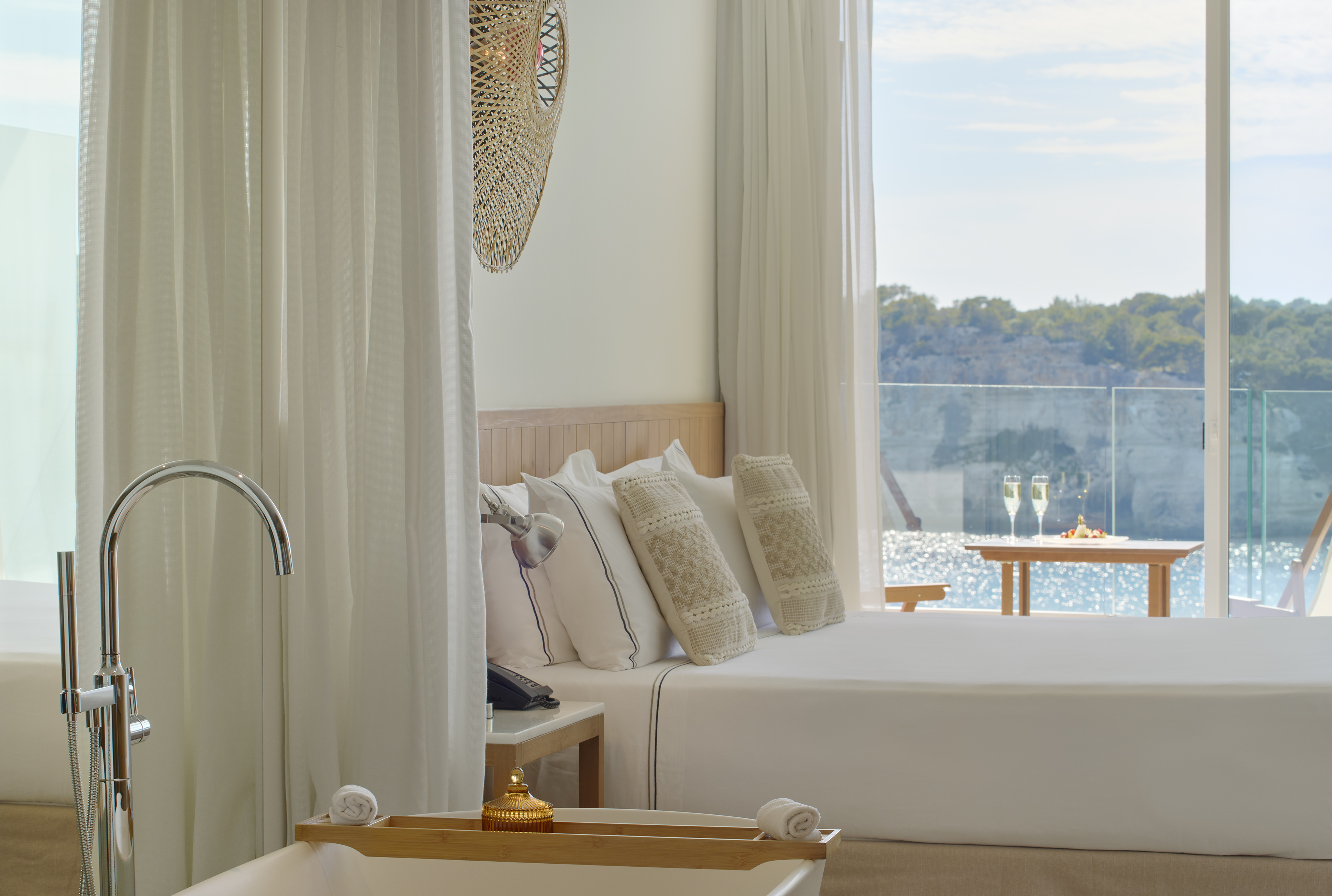 a bed with pillows in a room with a view of water and trees