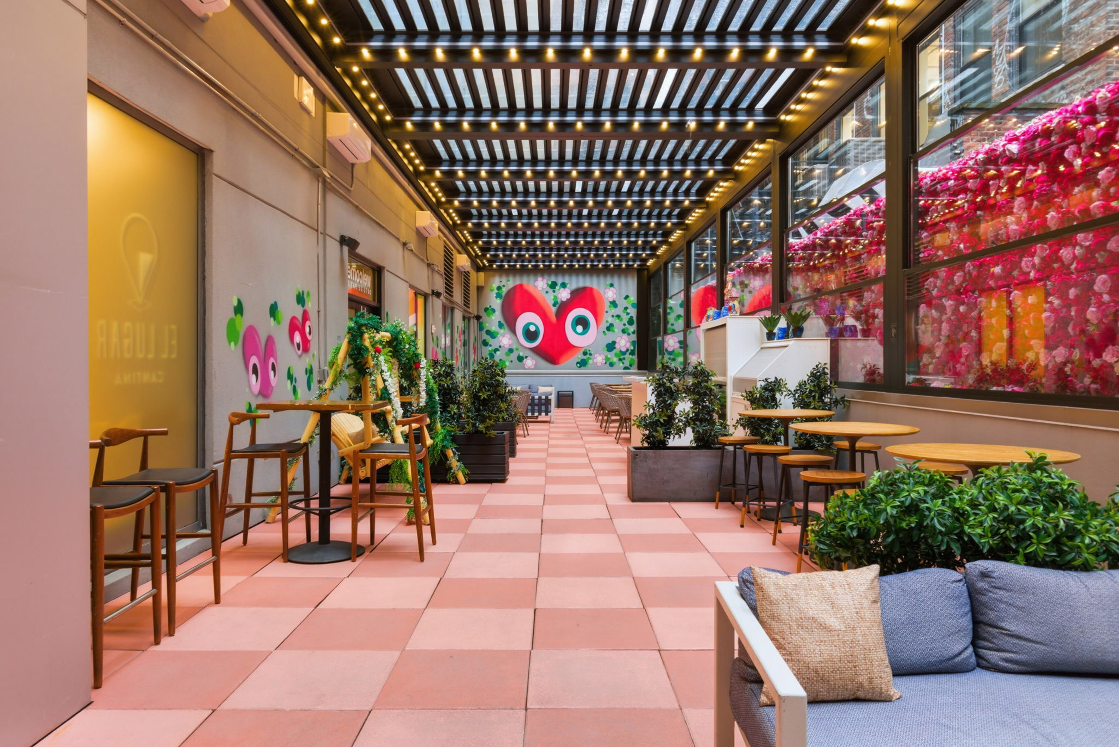 Vibrant restaurant patio with red heart mural, string lights, and floral windows.