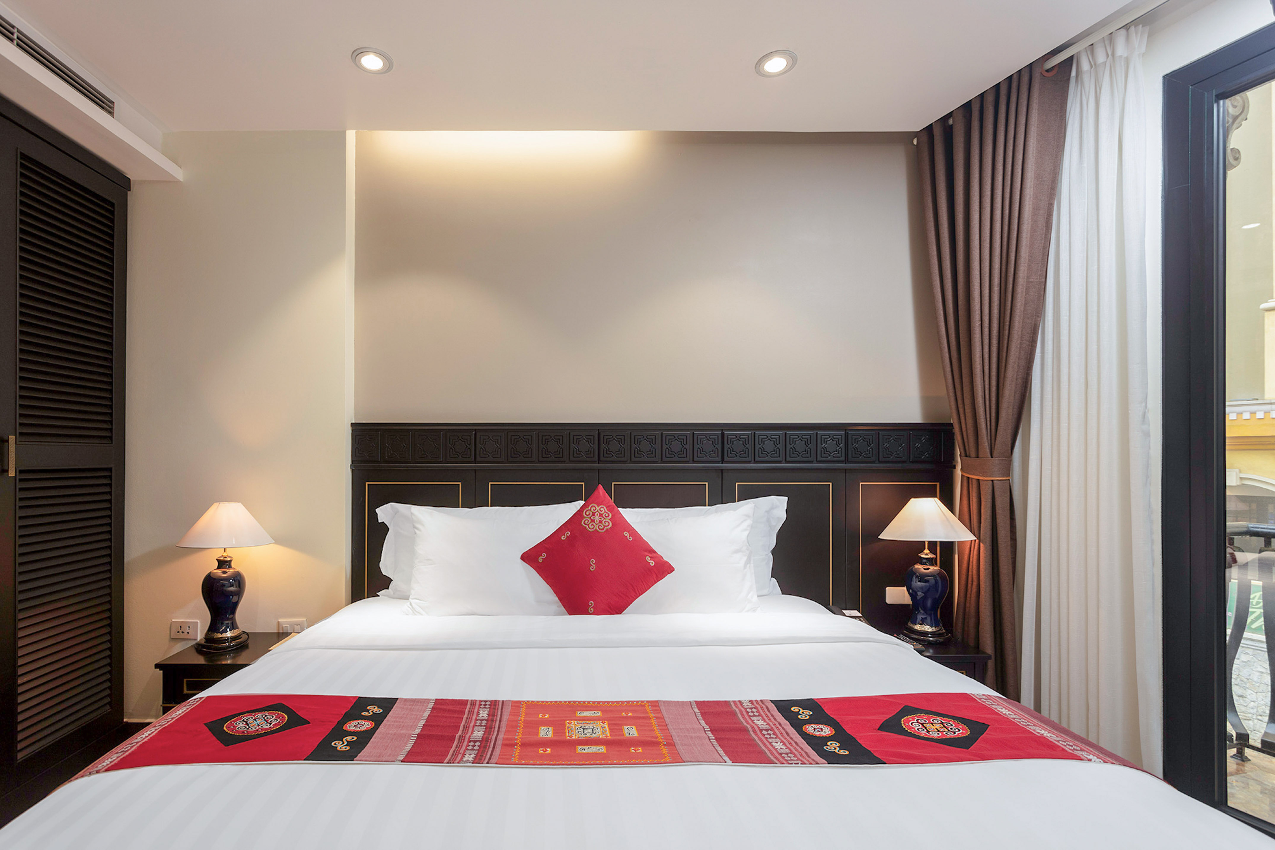 Elegant hotel bedroom with king bed, ornate headboard, and cultural accents.