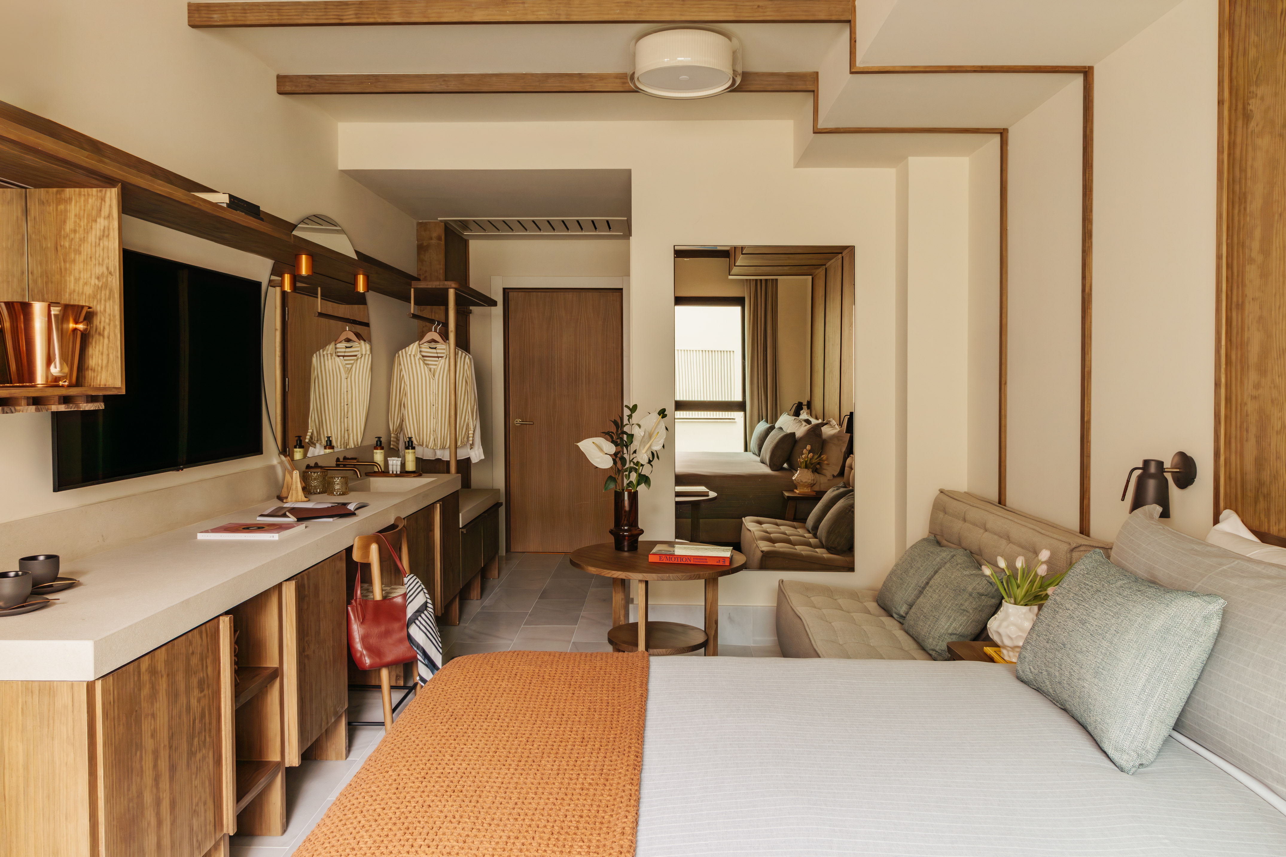 Stylish modern hotel room with wood accents, bed, and integrated vanity.