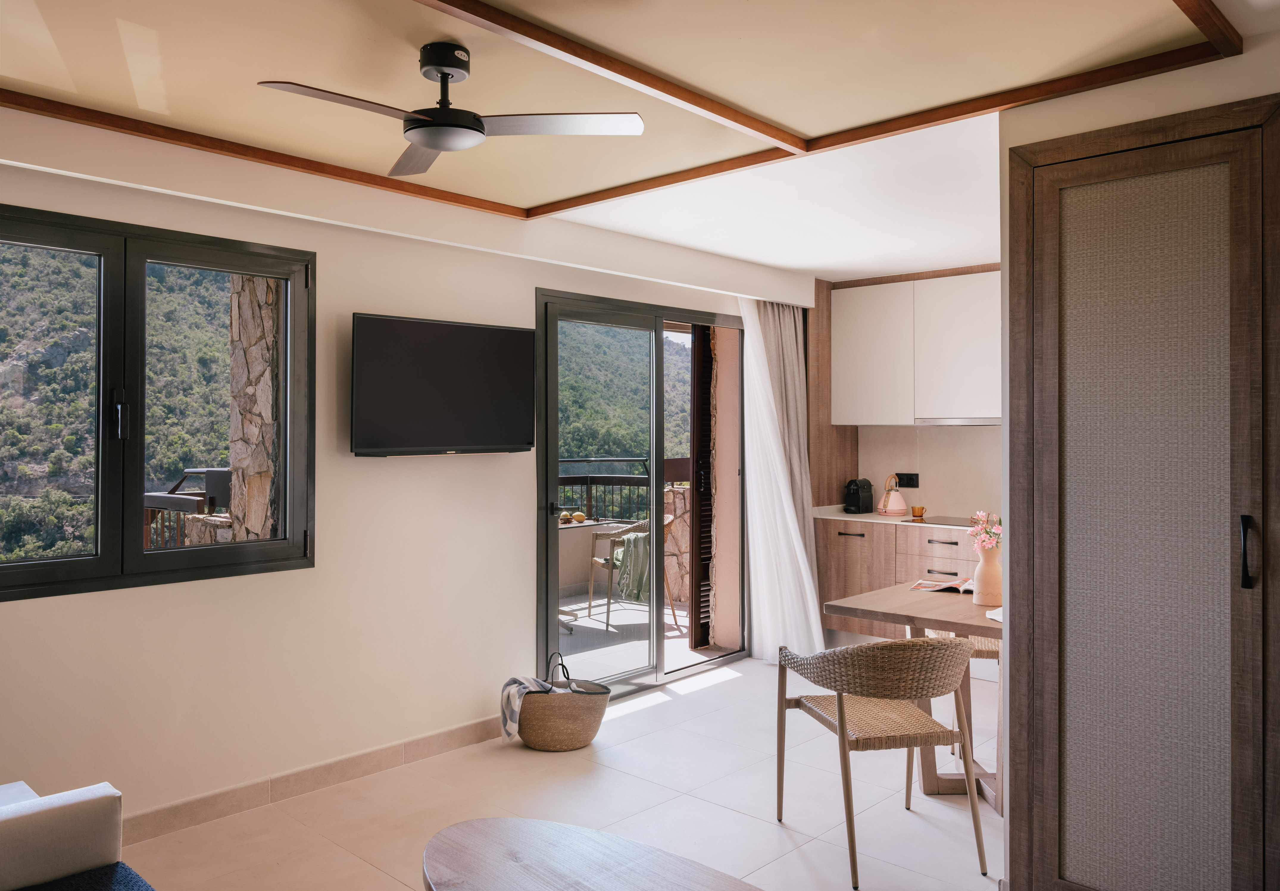 Modern hotel suite with mountain view, balcony, living area, and kitchenette.