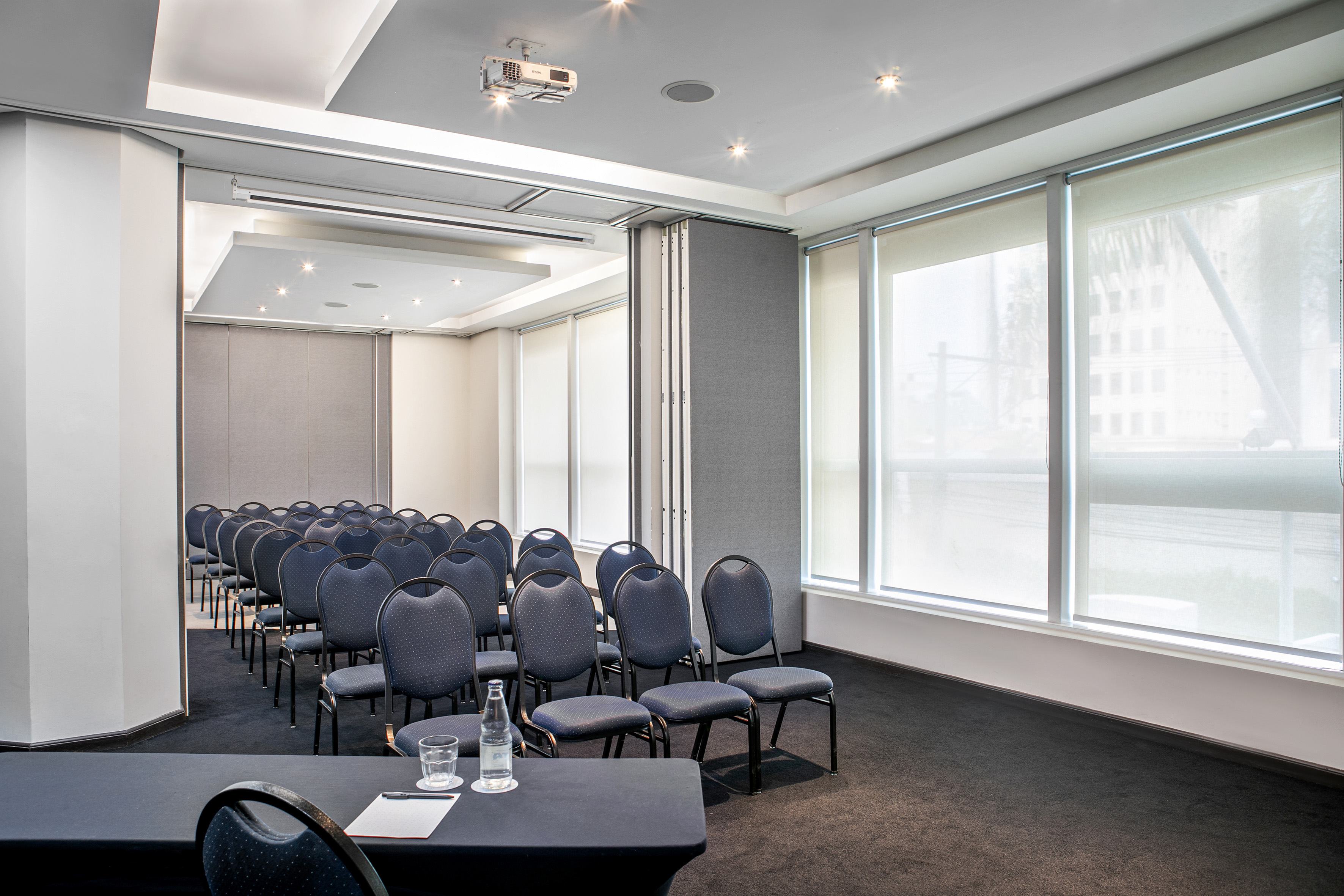 Modern meeting room set up with blue chairs, projector, and natural light.