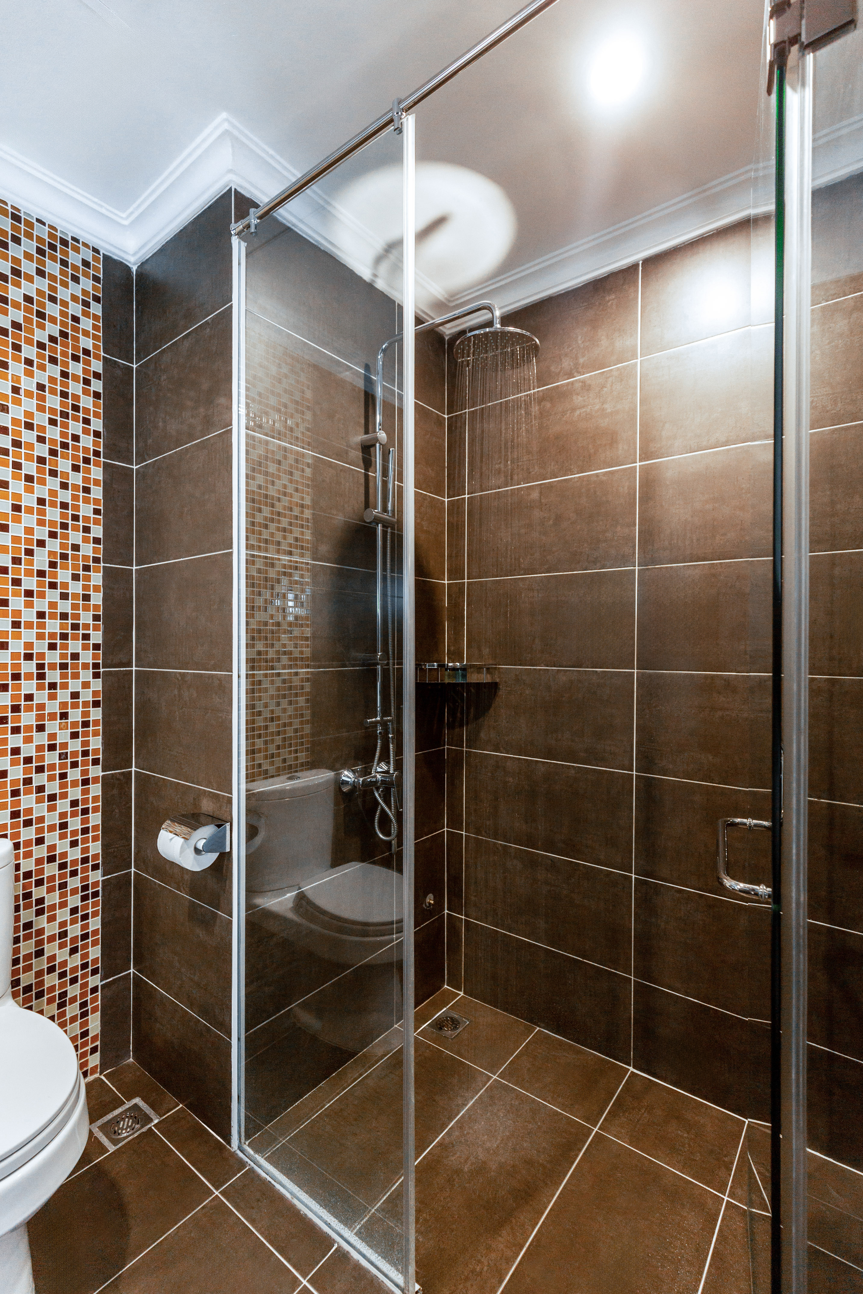 Bathroom with glass shower, rain shower, brown tiles, mosaic accents, toilet. - Deluxe Room - Hotel Sapa Square Affiliated by Meliá, Sapa