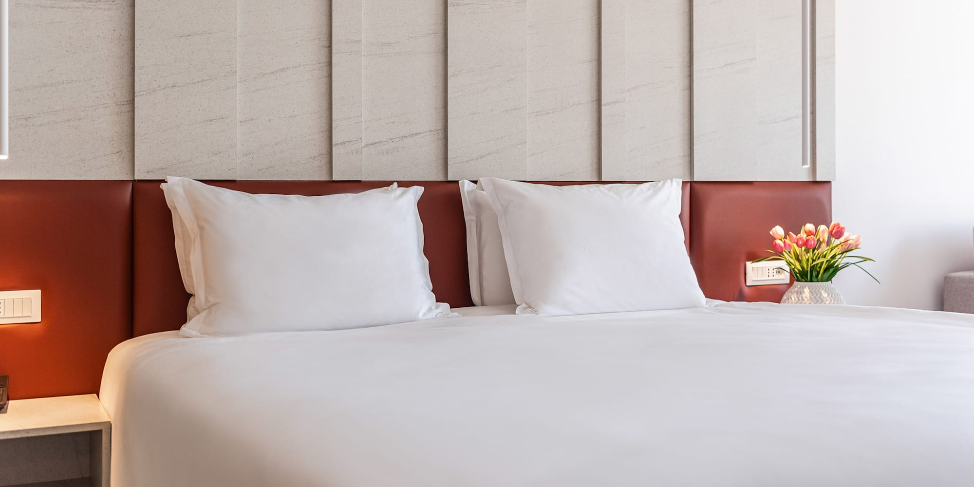 a bed with white sheets and a vase of flowers