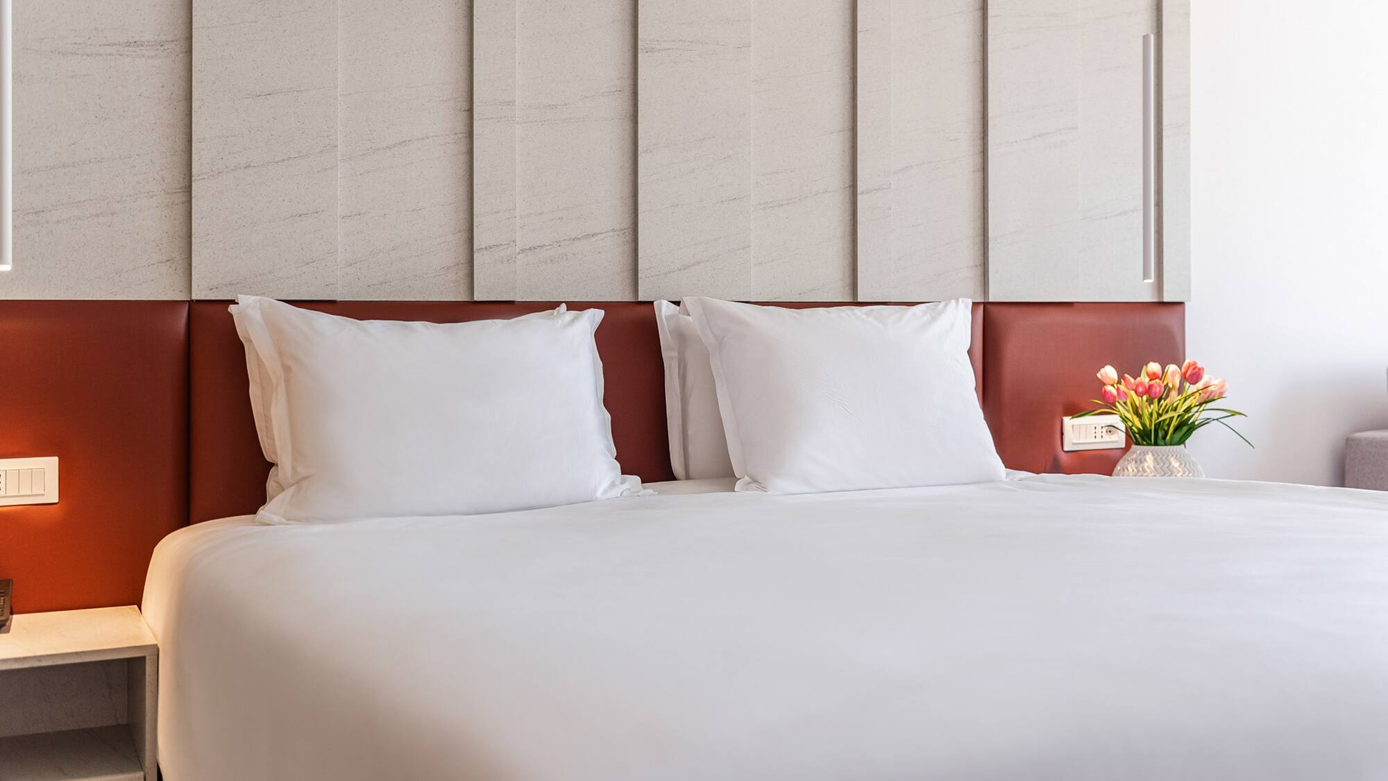 a bed with white sheets and a vase of flowers