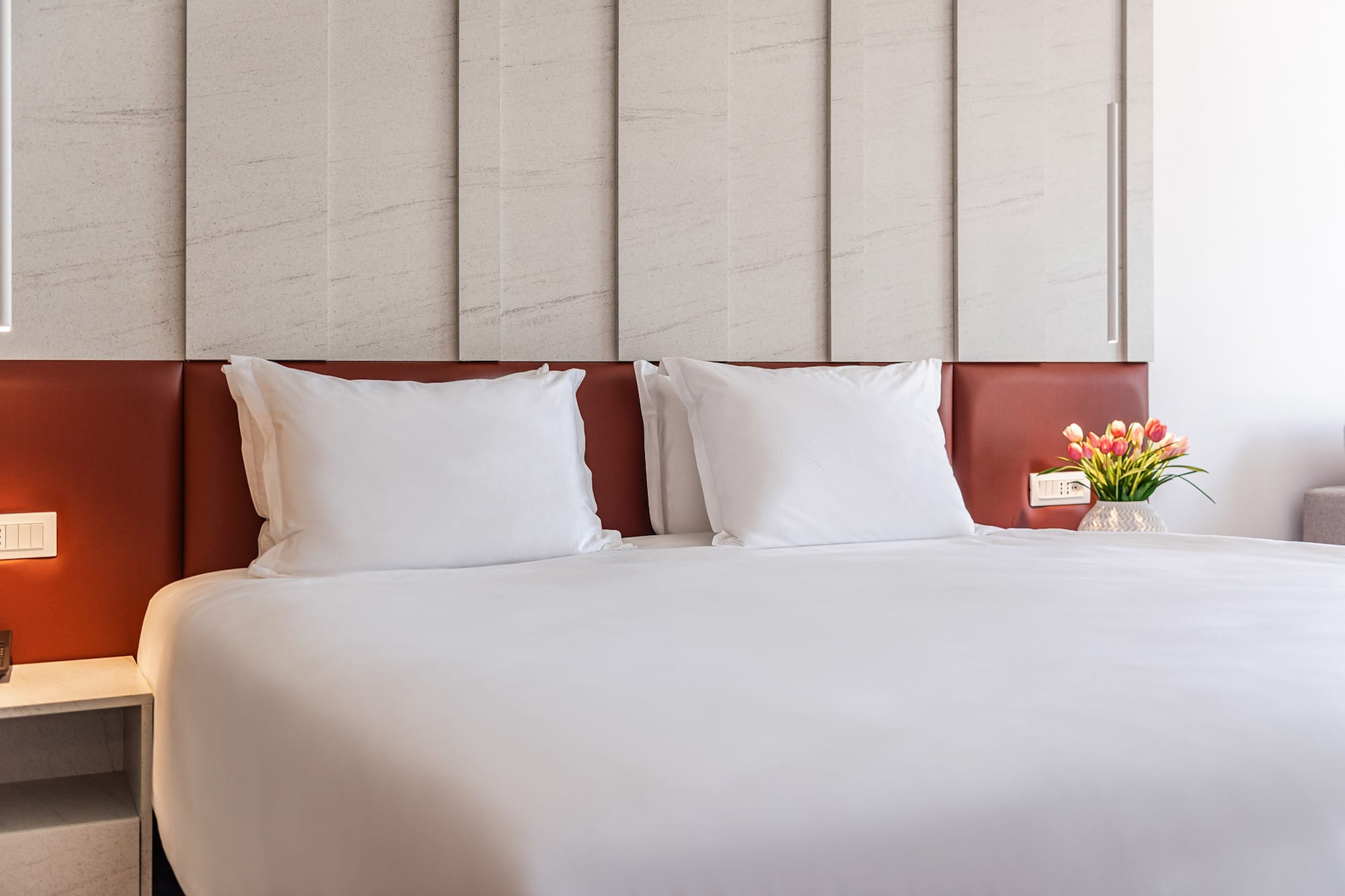 a bed with white sheets and a vase of flowers