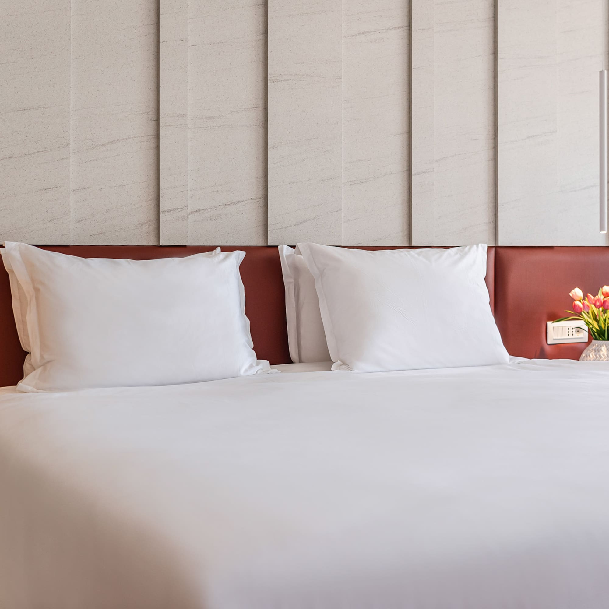 a bed with white sheets and a vase of flowers
