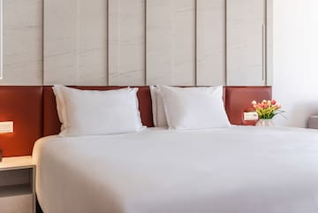 a bed with white sheets and a vase of flowers