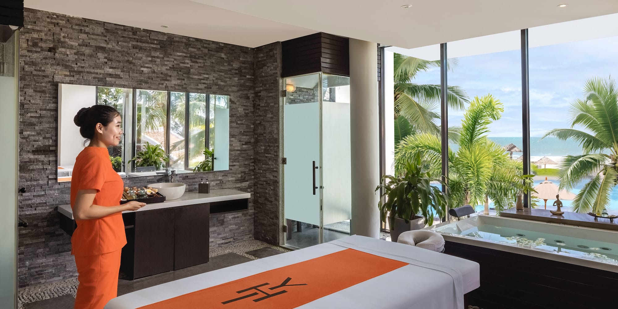 a woman in orange uniform standing in a room with a jacuzzi and a pool