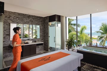 a woman in orange uniform standing in a room with a jacuzzi and a pool