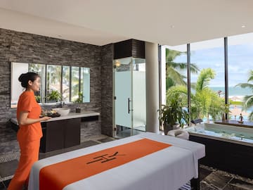 a woman in orange uniform standing in a room with a jacuzzi and a pool