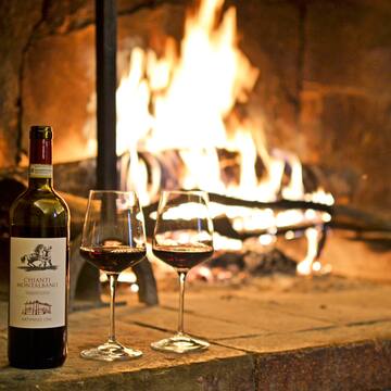 a bottle of wine and two glasses of wine in front of a fireplace