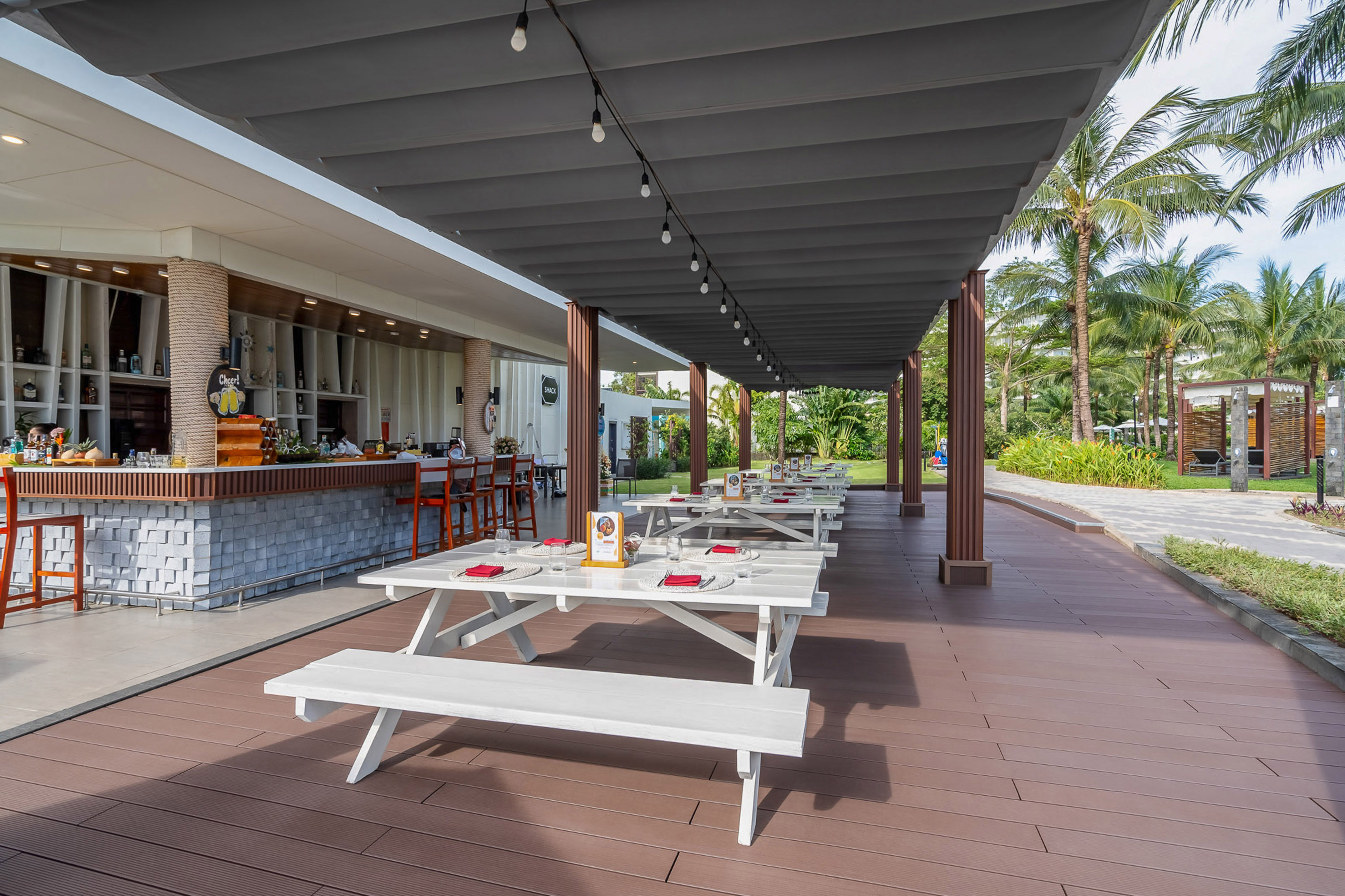 Tropical outdoor bar and restaurant patio with string lights and palm trees.