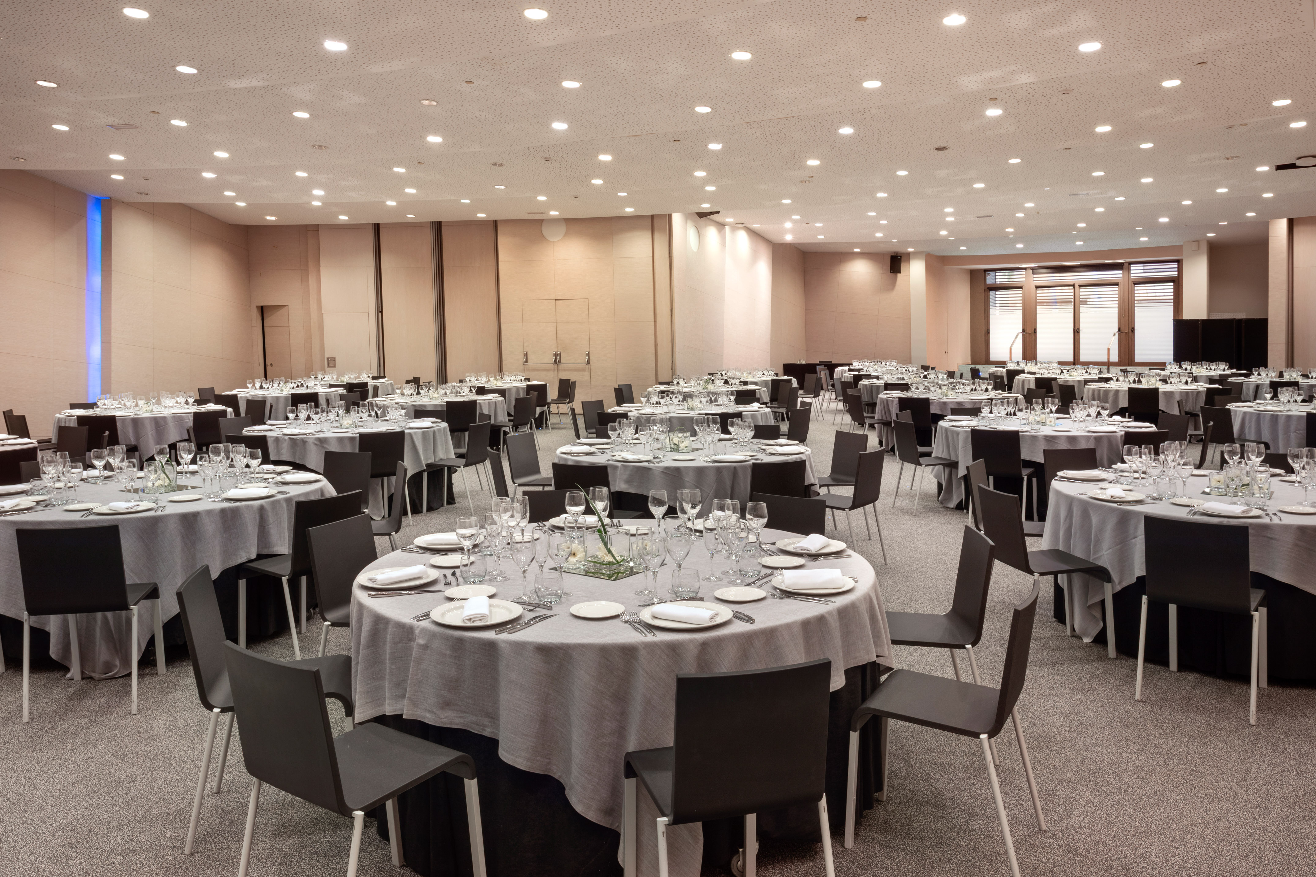 Large banquet hall set with numerous round tables for corporate events.