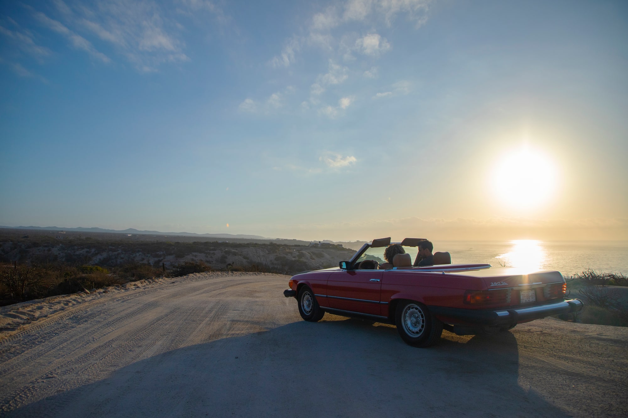 a car on a road with a body of water in the background