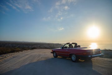 a car on a road with a body of water in the background