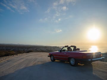 a car on a road with a body of water in the background