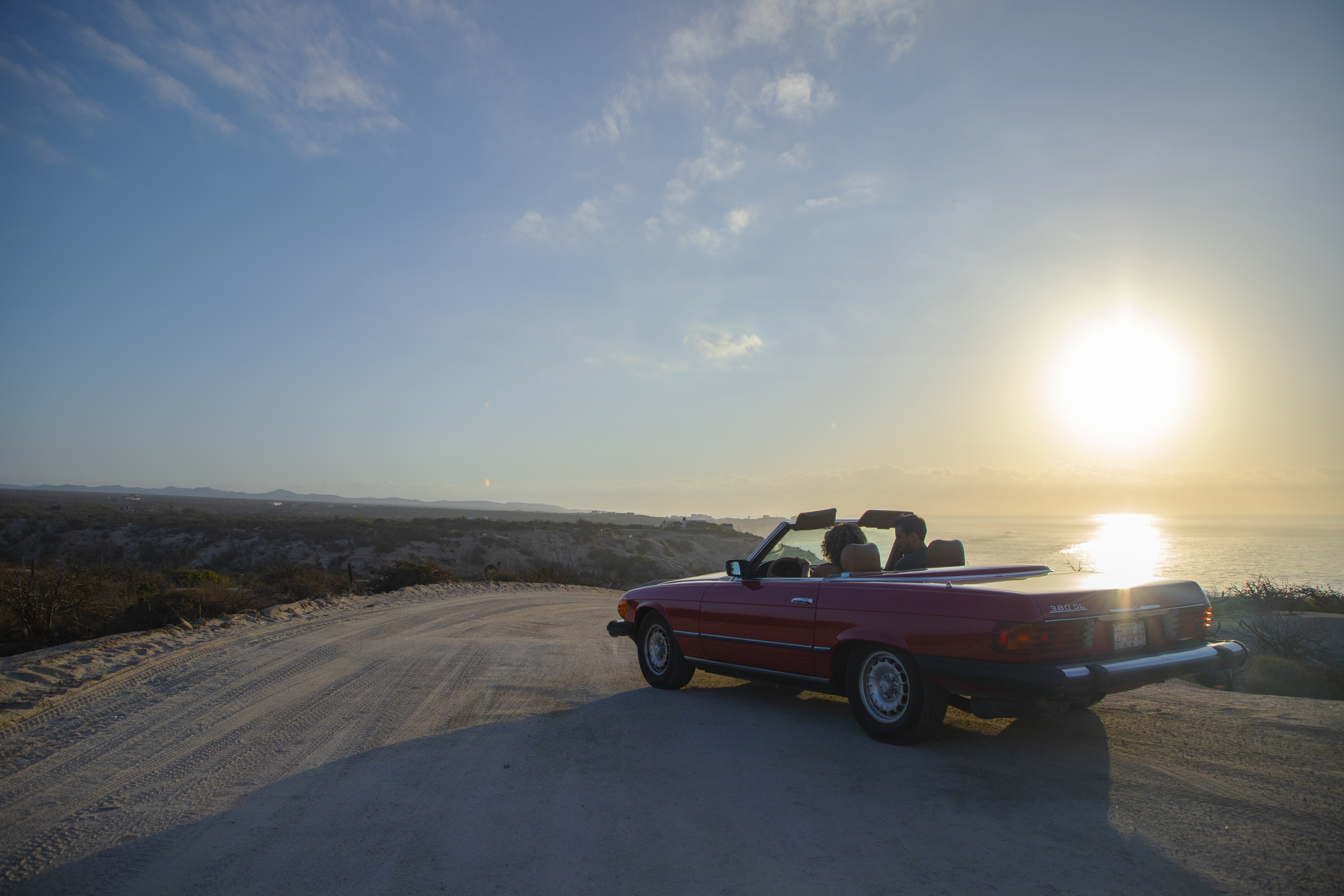 a car on a road with a body of water in the background