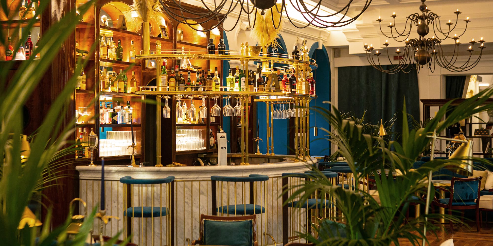 a bar with a chandelier and shelves of wine glasses