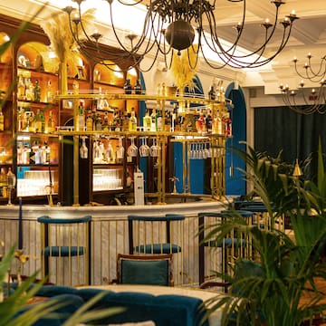 a bar with a chandelier and shelves of wine glasses