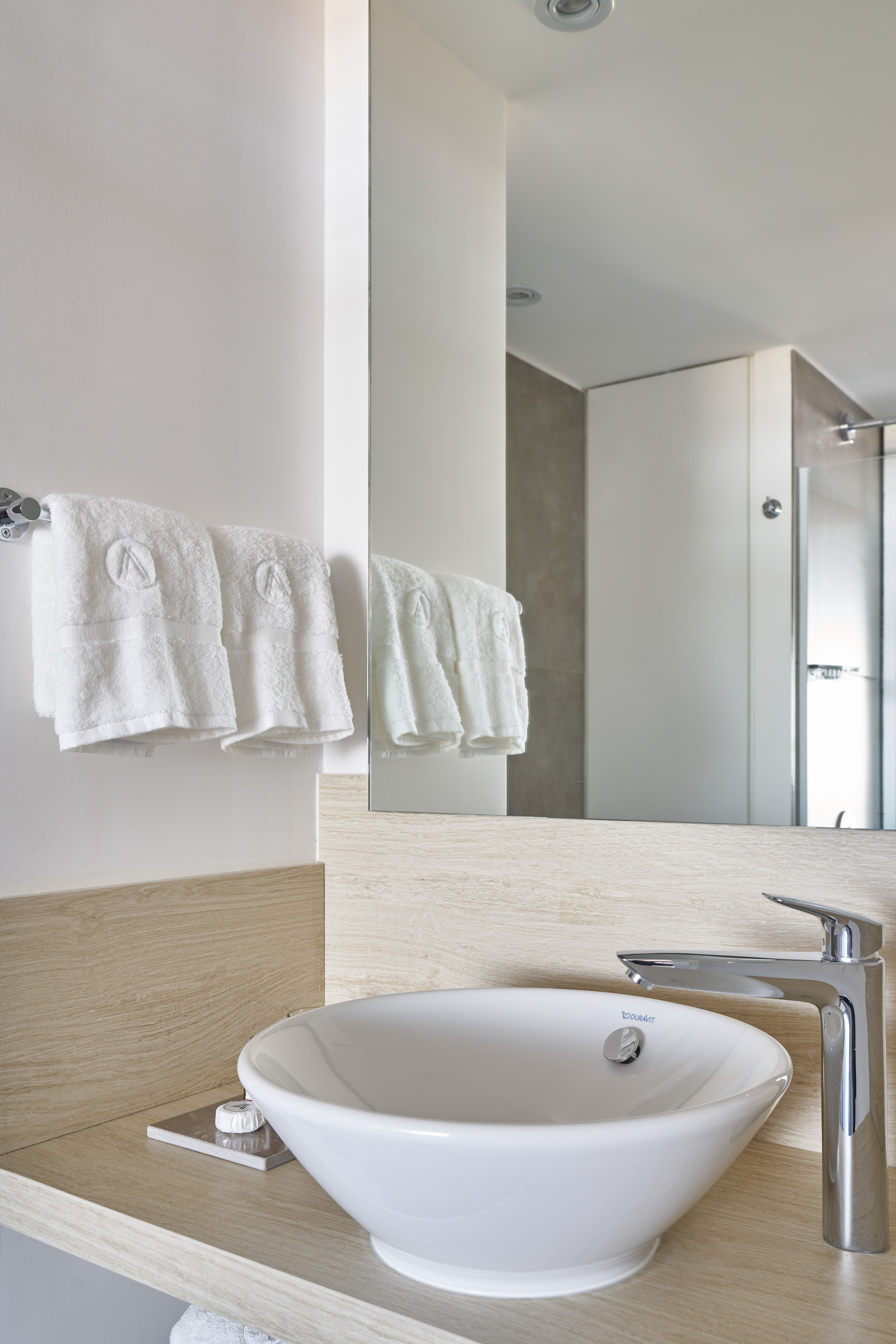 Modern bathroom vanity with white vessel sink, chrome faucet, and wooden counter.