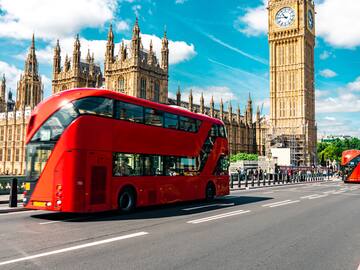 a double decker bus on a street in front of a clock tower