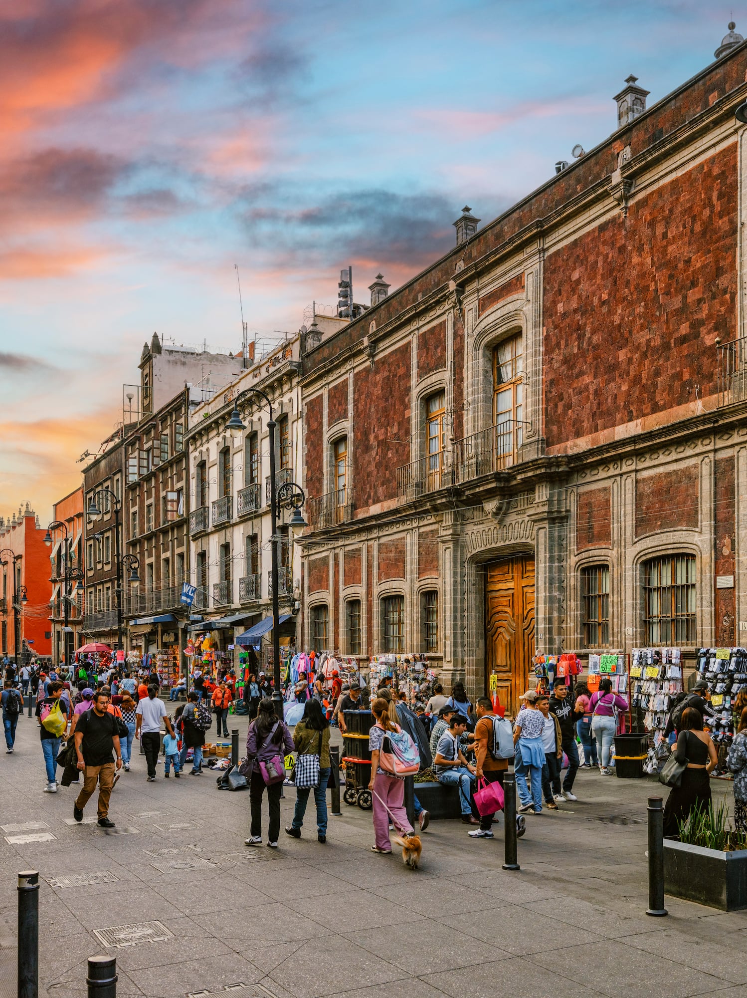 Calle concurrida en CDMX, edificios históricos, Catedral, cielo atardecer.