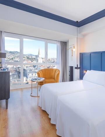 a room with two beds and a chair and a window