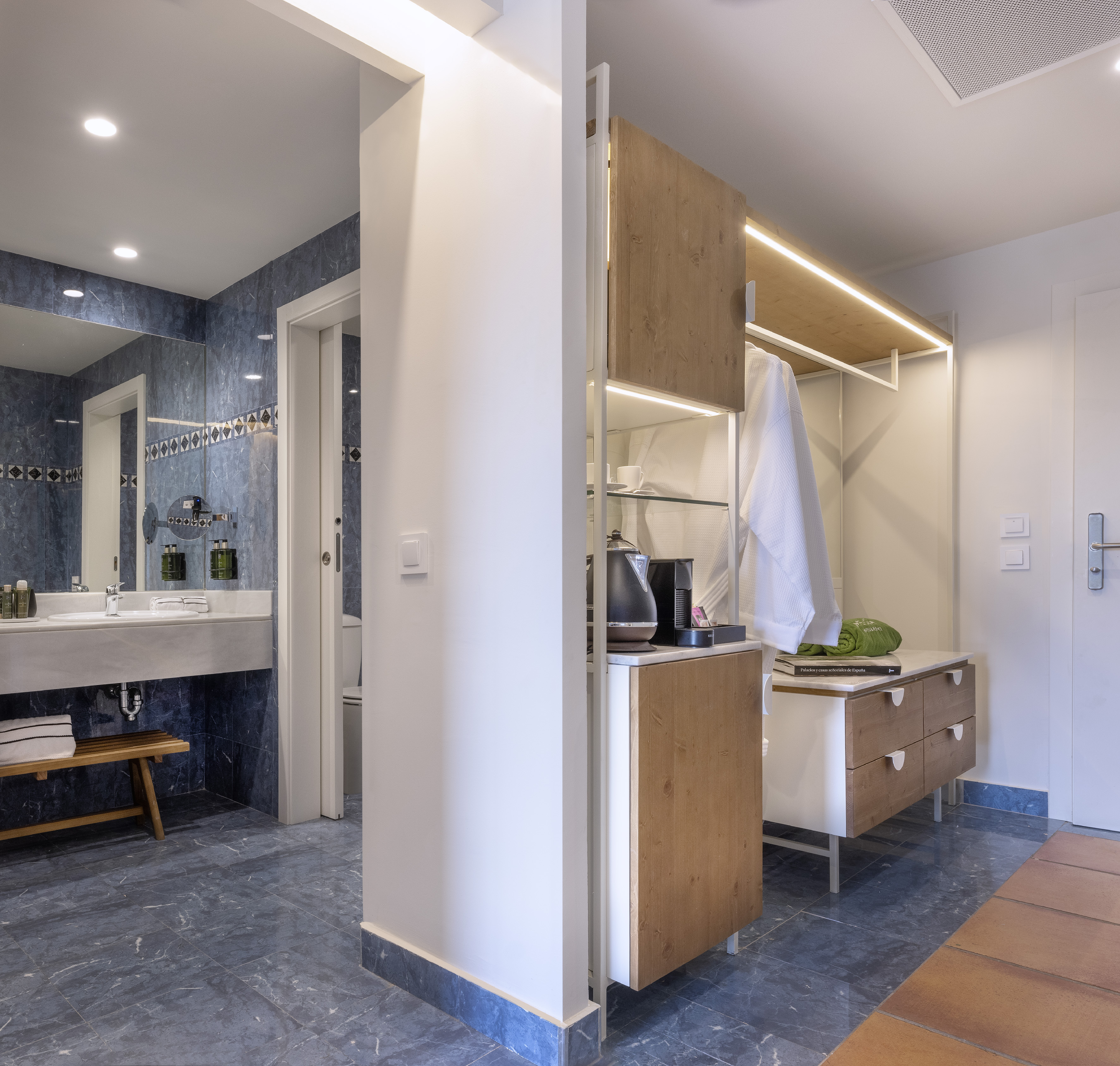 Blue marble hotel bathroom and modern open closet with coffee setup.