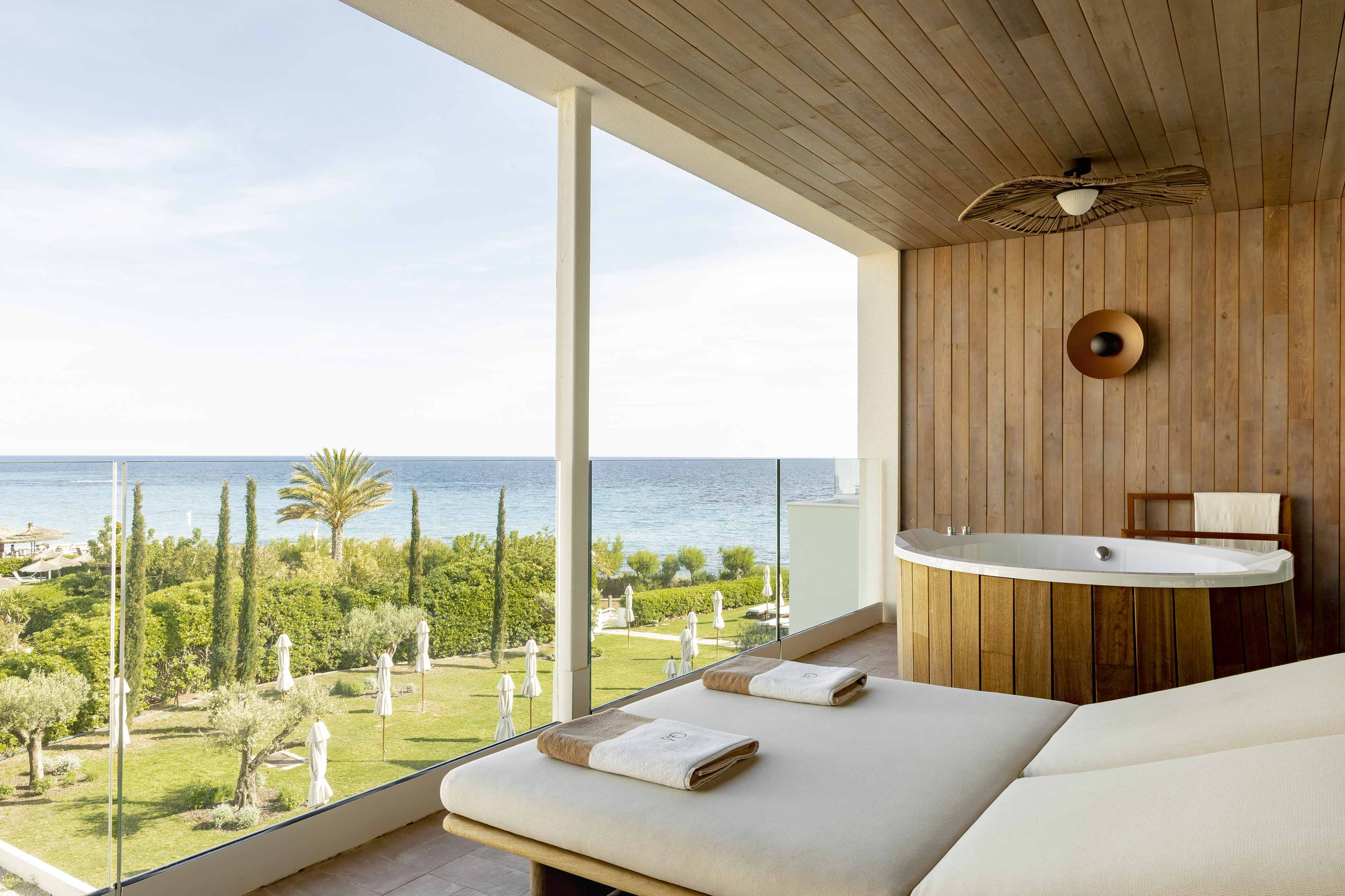 Luxury beachfront balcony with ocean view, daybed, and hot tub.