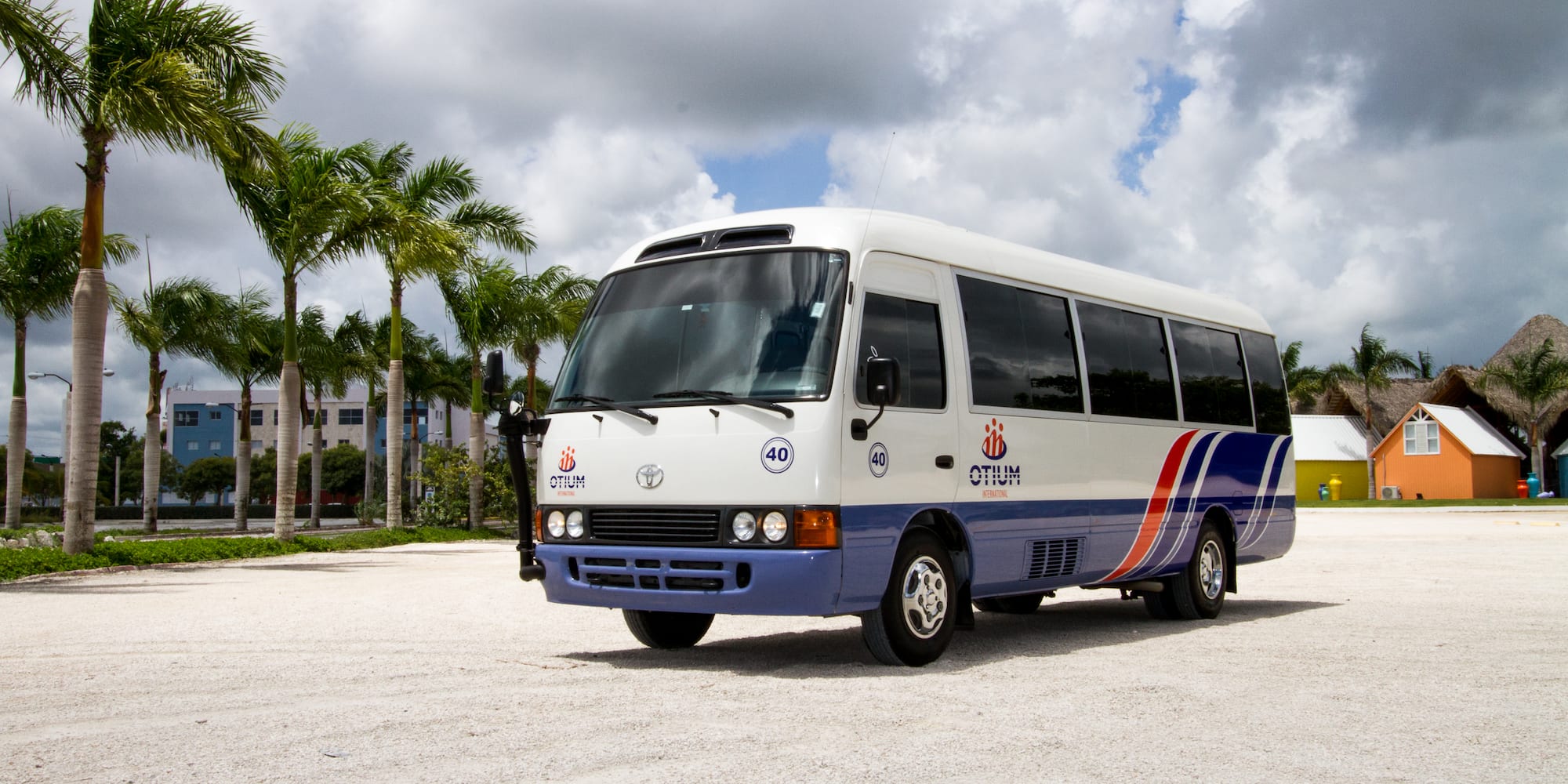 a white and blue bus parked on a gravel road