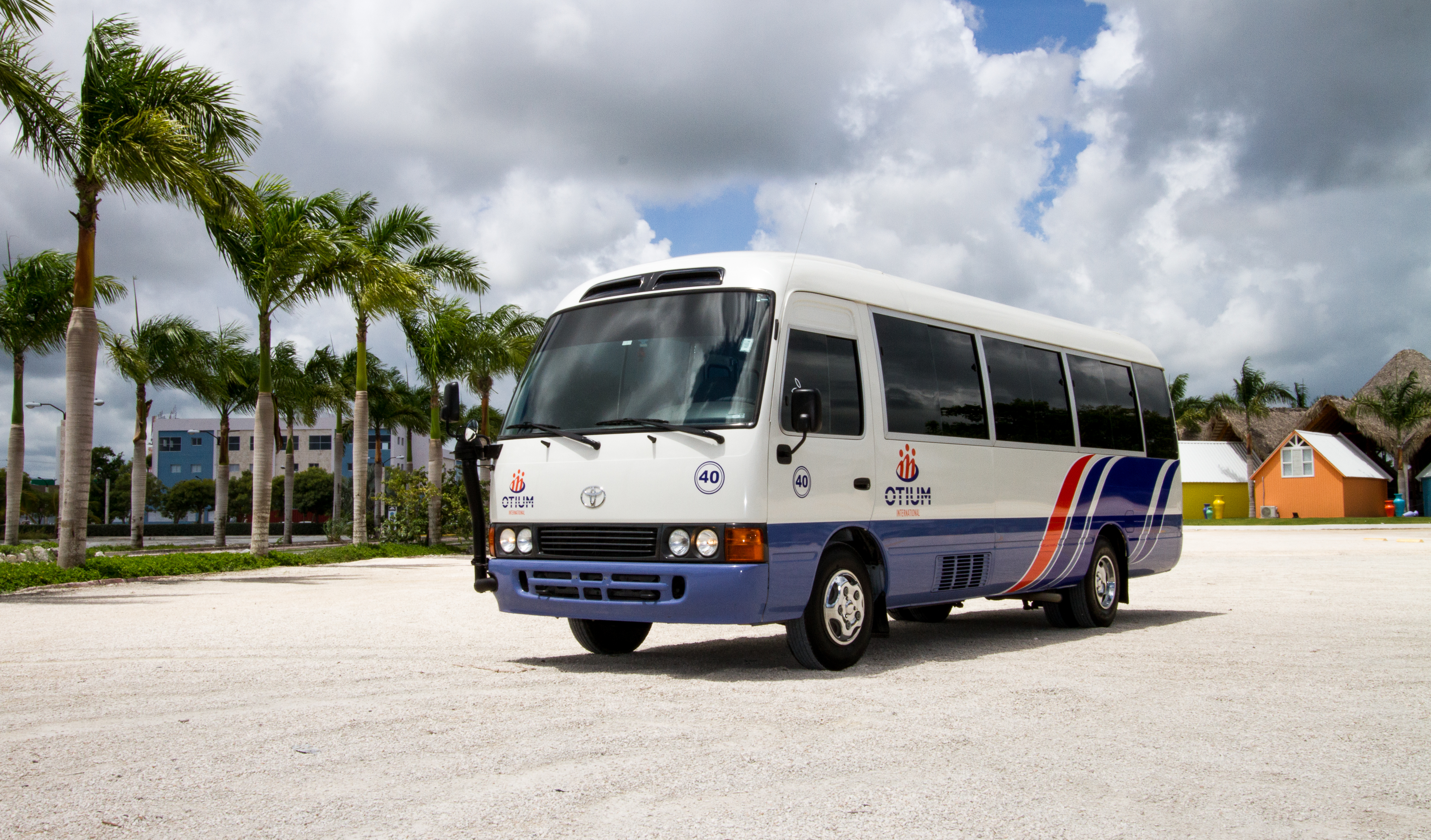 a white and blue bus parked on a gravel road