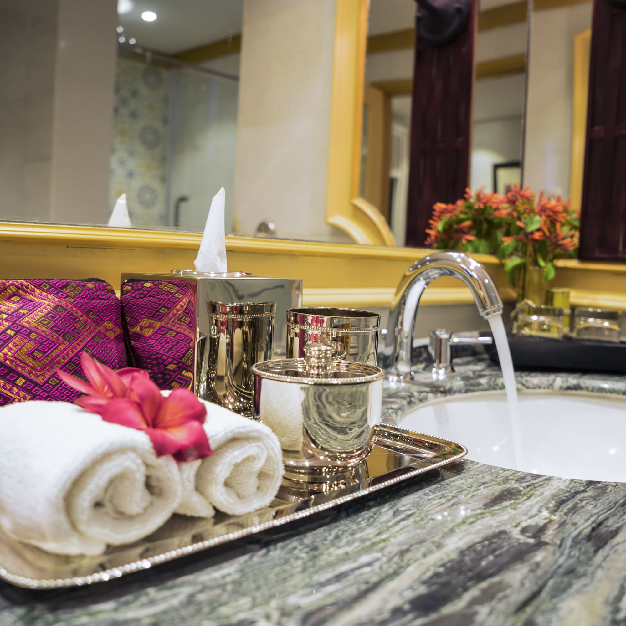 a bathroom sink with a tray of towels and a flower on it