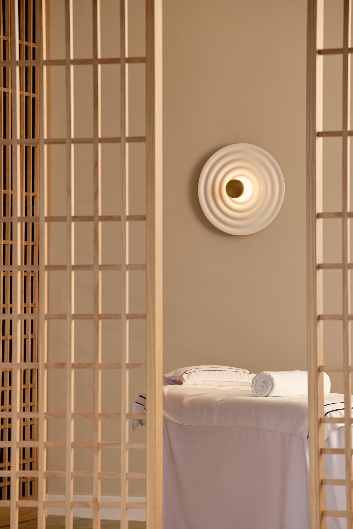 a room with a bed and a wall with a light on the wall